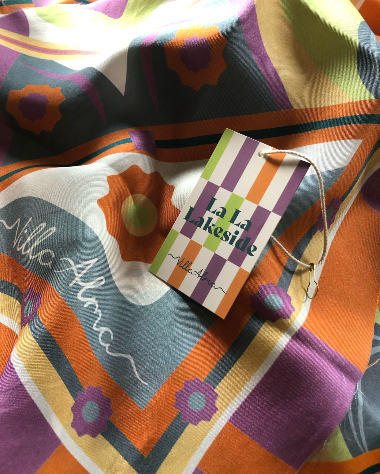 Bunte Stoffbahn mit Frühlingsmotiv und einem Anhänger mit der Aufschrift "La La Lakeside".