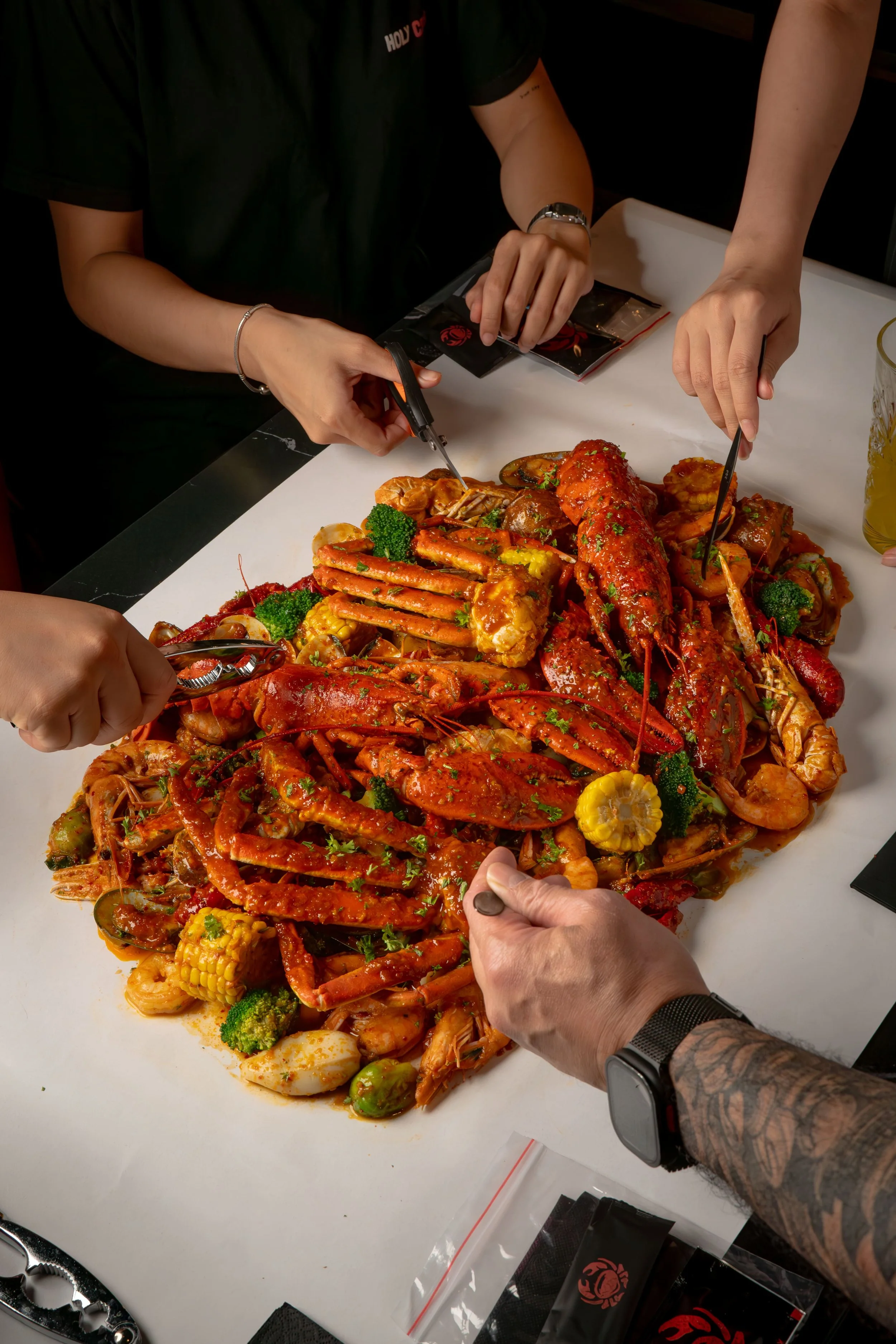 Seafood boil spread at Holy Crab Helsinki with snow crab legs, lobster, clams, corn, potatoes and two house sauces