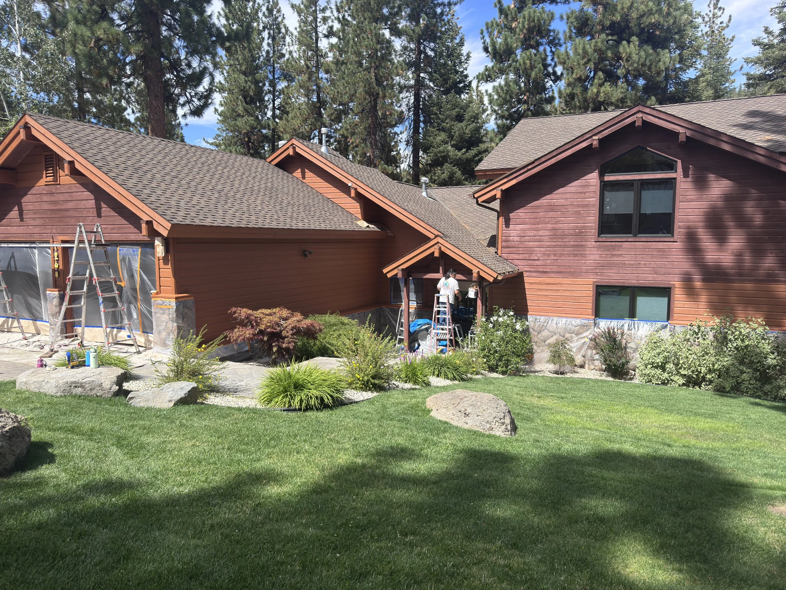 rew staining wood siding on a mountain home with the windows and stonework masked off in zephyr cove