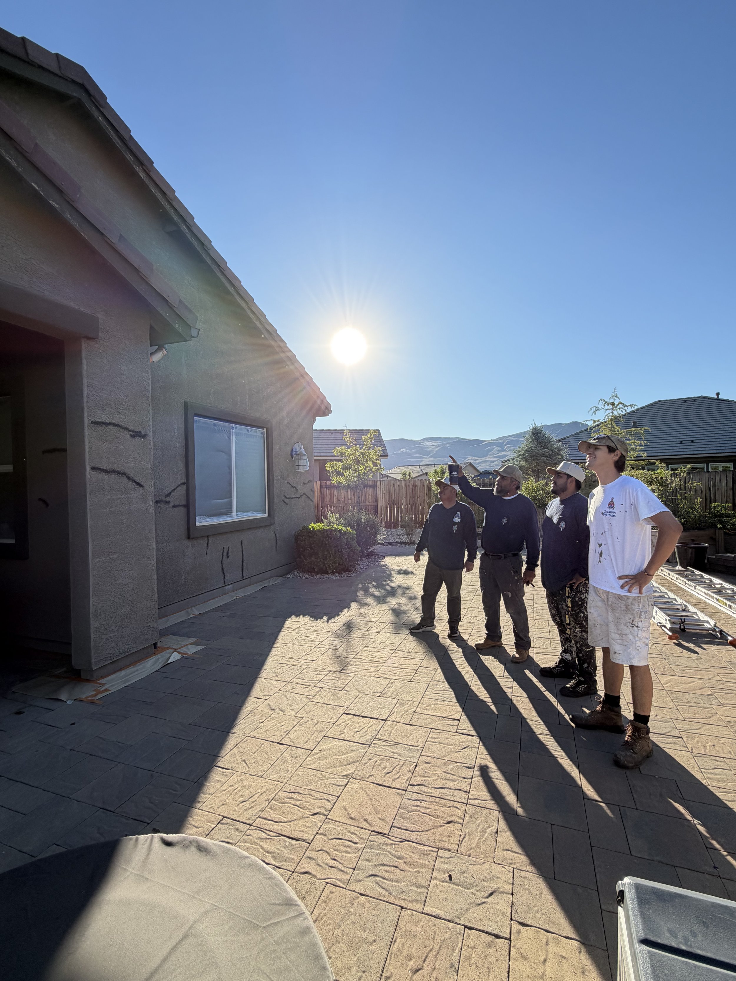 Colourscape crew walking a stucco home before painting, with cracks marked for repair
