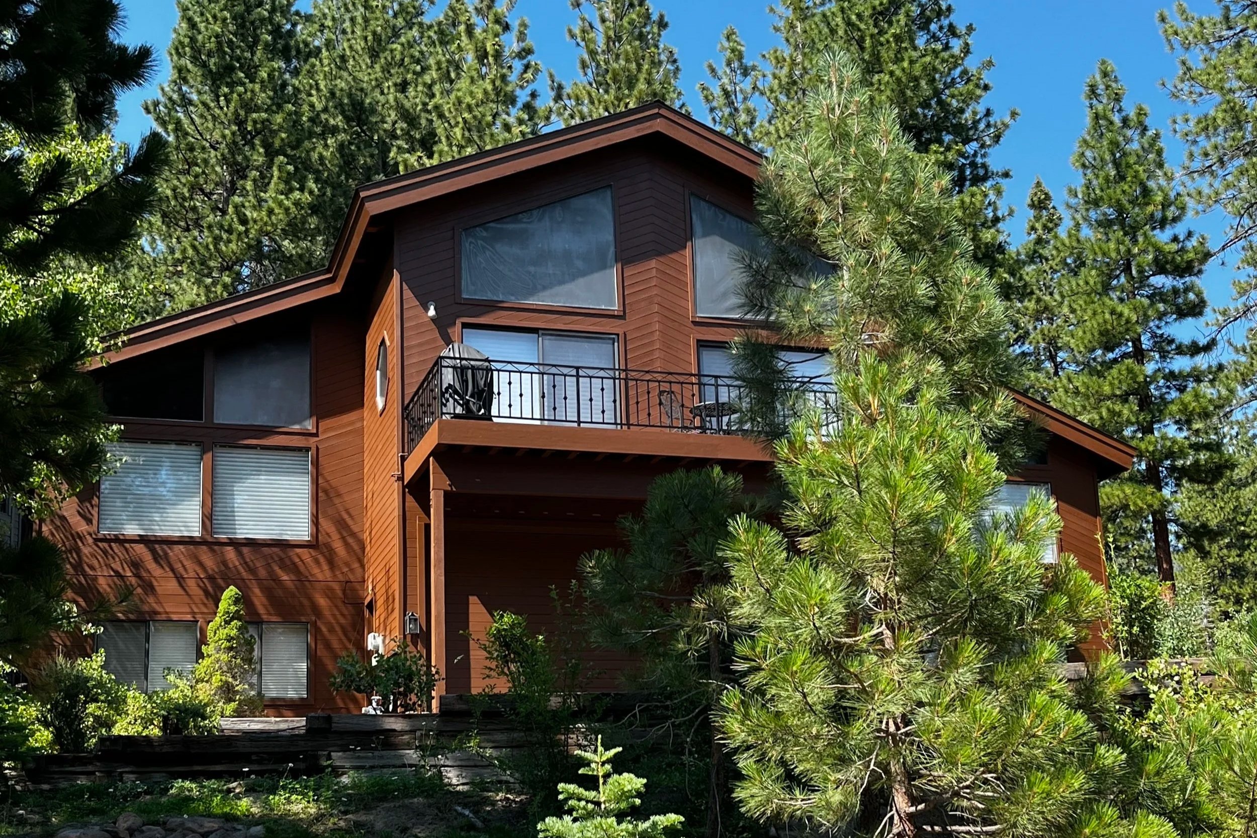 Two-story wood-sided home with fresh paint and an iron balcony railing among the pines in Incline Village