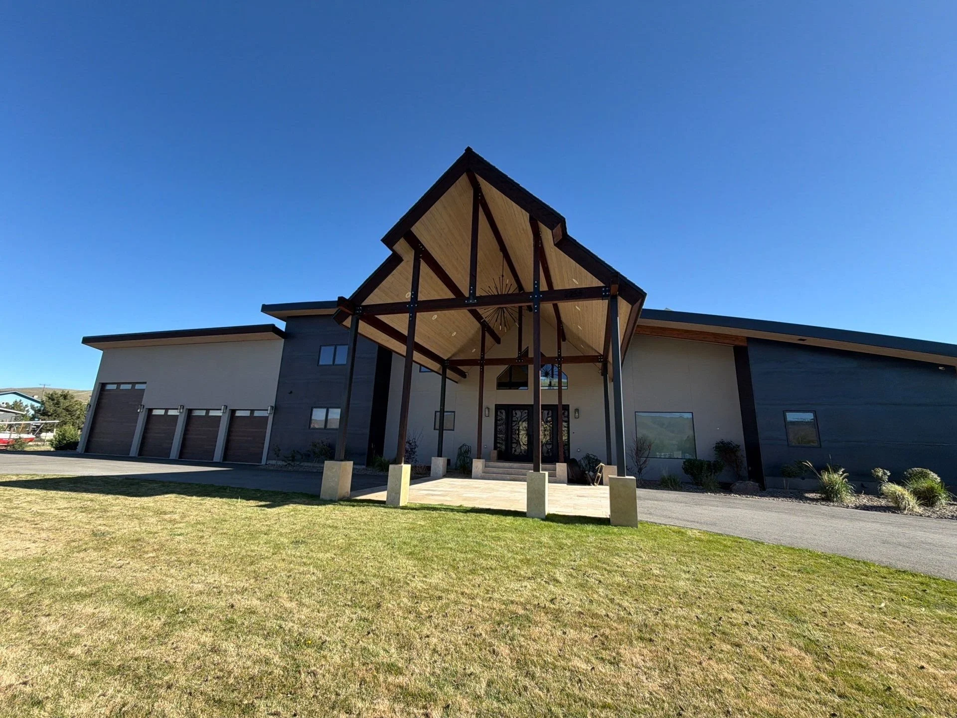 Modern home with a stained timber entry canopy, stucco and dark siding on an open lot in Verdi