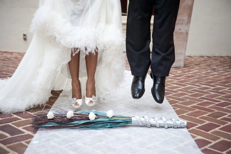 A couple jumping over the broom as a part of their wedding ceremony