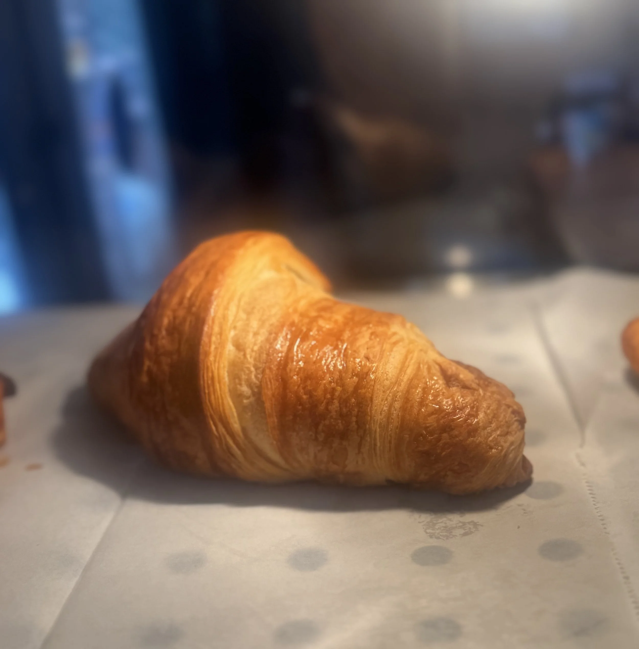 A golden-brown croissant on a piece of parchment paper.