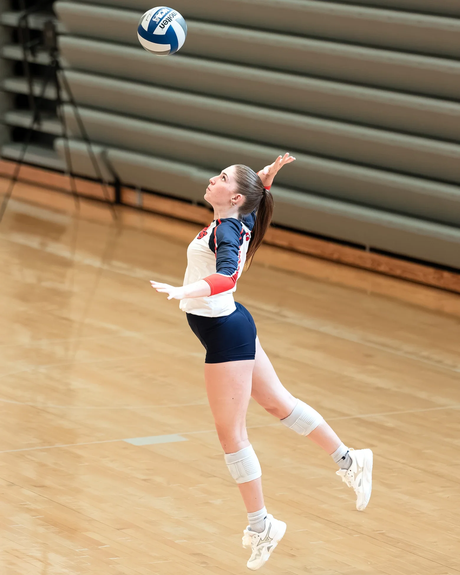 female volleyball player leaping for ball on serve