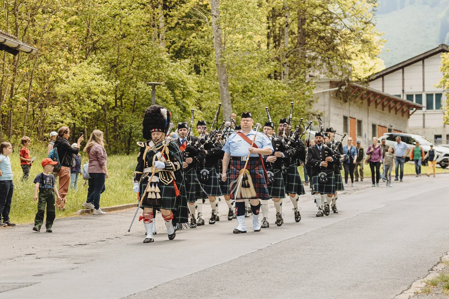 Pfeifer im traditionellen schottischen Kilt in einer Parade, begleitet von Offizieren in historischen Uniformen.