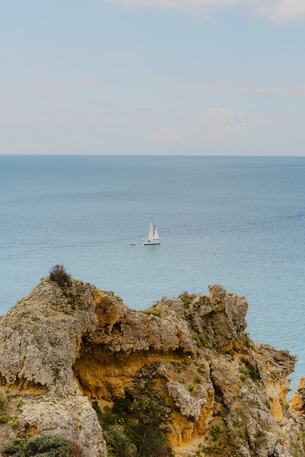 Meer mit Segelboot vor Felsen in Portugal