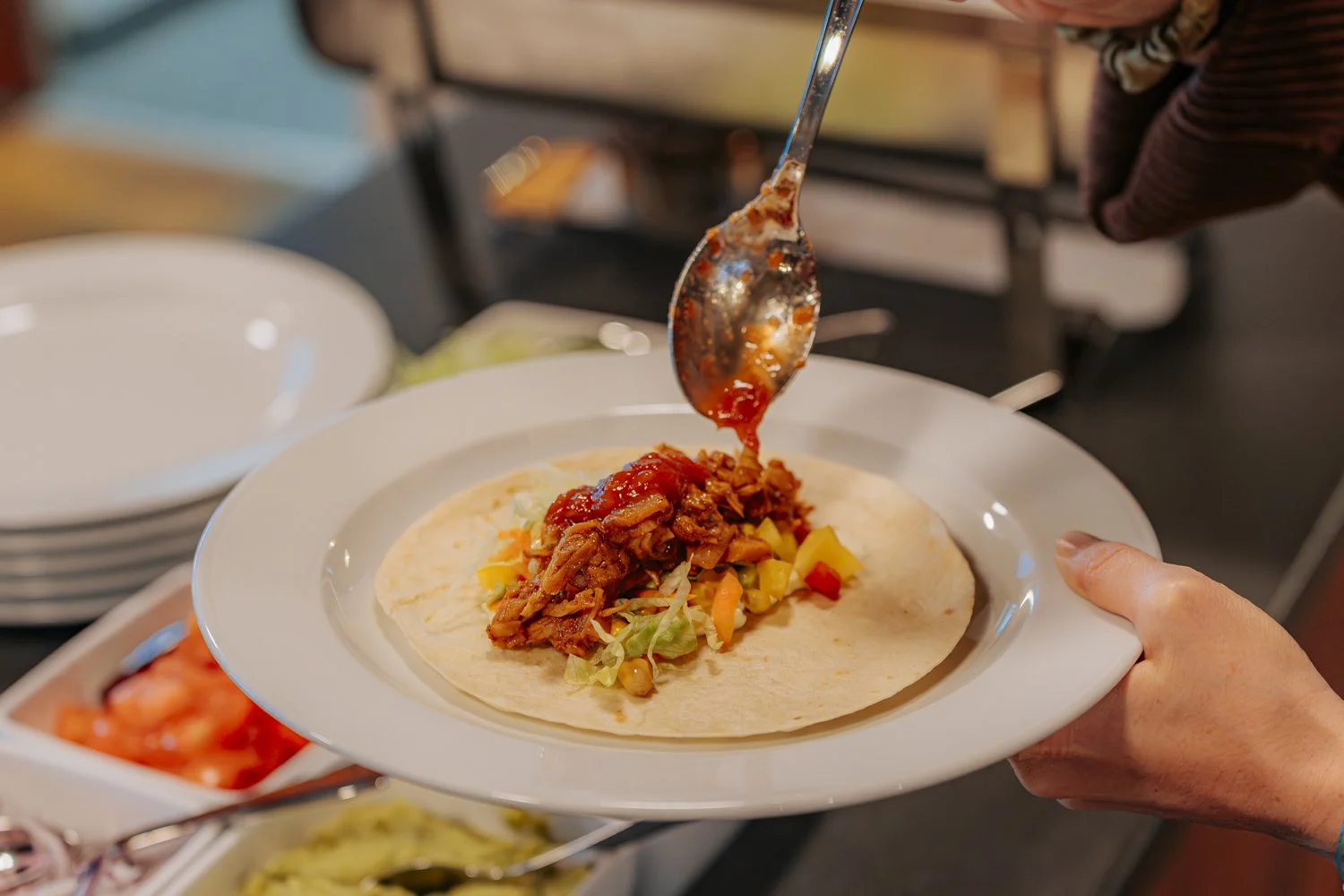 Person füllt eine Tortilla mit Salat und Fleisch