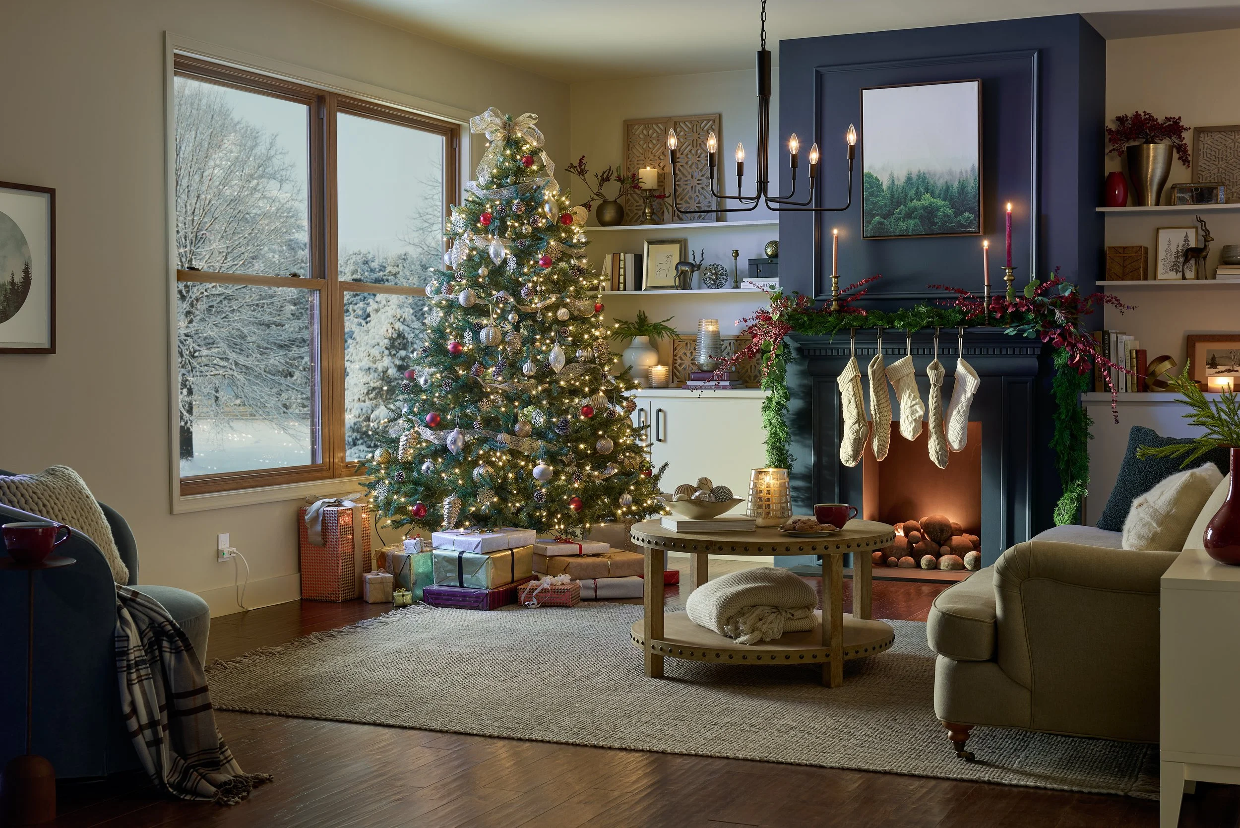 A cozy living room decorated for Christmas with a lit Christmas tree, wrapped gifts, and a fireplace with stockings hanging, surrounded by furniture and holiday decorations.