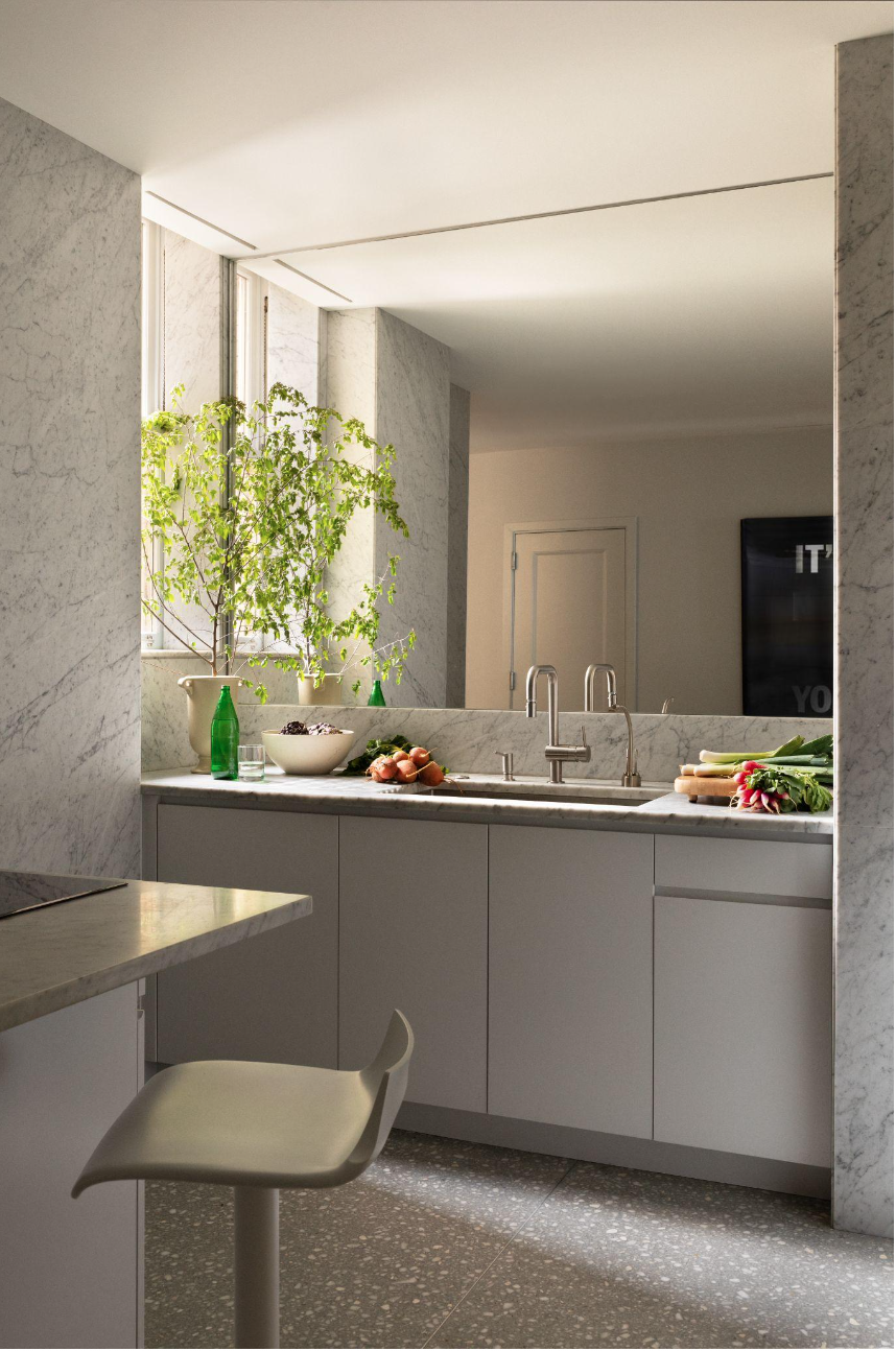 Kitchen with terrazzo floor, marble-wrapped surfaces, mirrored backsplash, and minimalist cabinetry.