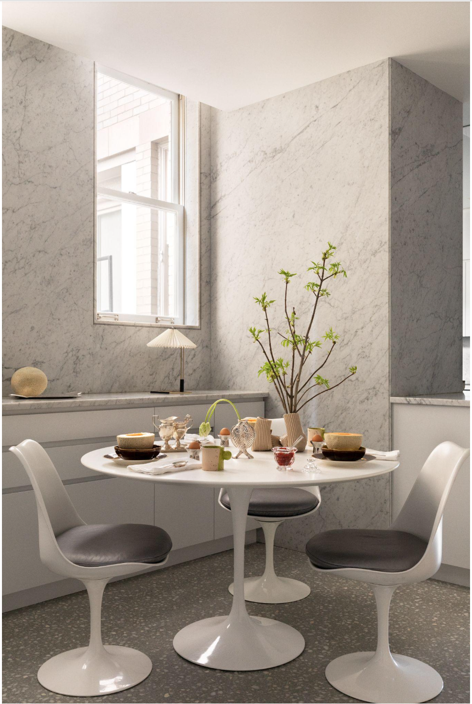Breakfast nook with a white Saarinen tulip table and chairs softening the clean, modern architecture.