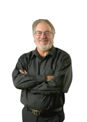 A smiling middle-aged man with glasses, gray hair, and a beard, wearing a black shirt with his arms crossed.