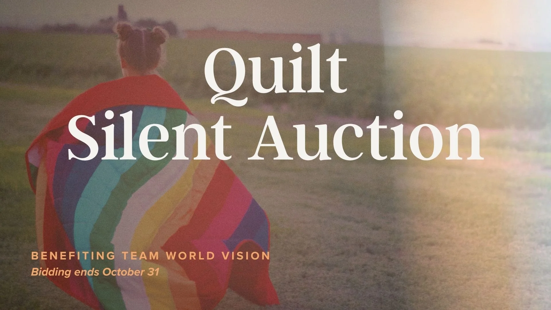 A person with two buns in their hair is sitting on grass holding a rainbow-colored kite with a long tail. The background shows a field and distant buildings at sunset. The overlay text reads: "Quilt Silent Auction" and additional details about bidding ending October 31.