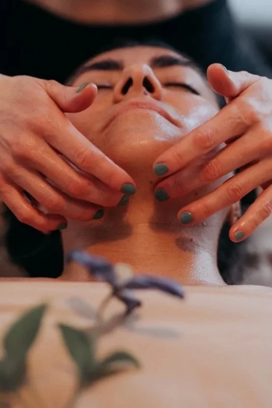 A woman receiving a facial massage for jaw tension relief, TMJ support, lymphatic drainage, relaxation and nervous system support in Edmonton.