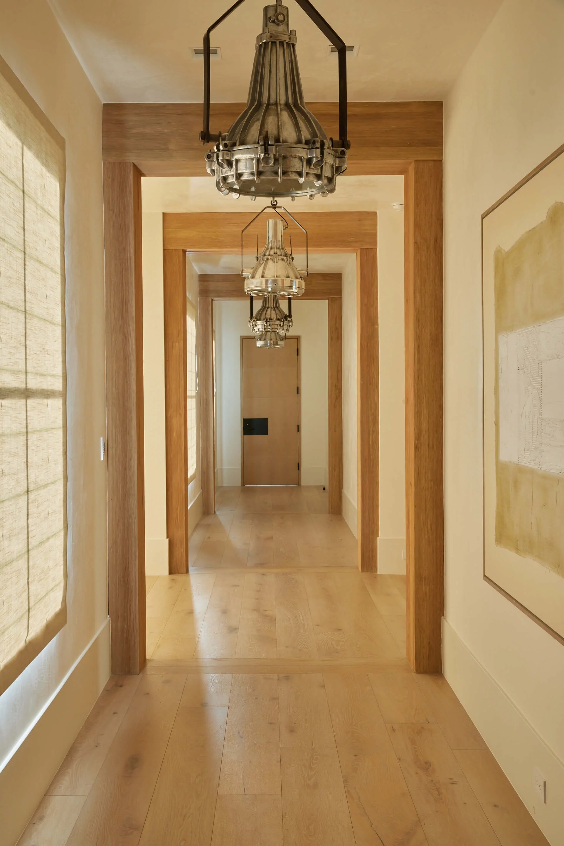 HAllway with wood beam arches and unique light fixates in Mesa custom home