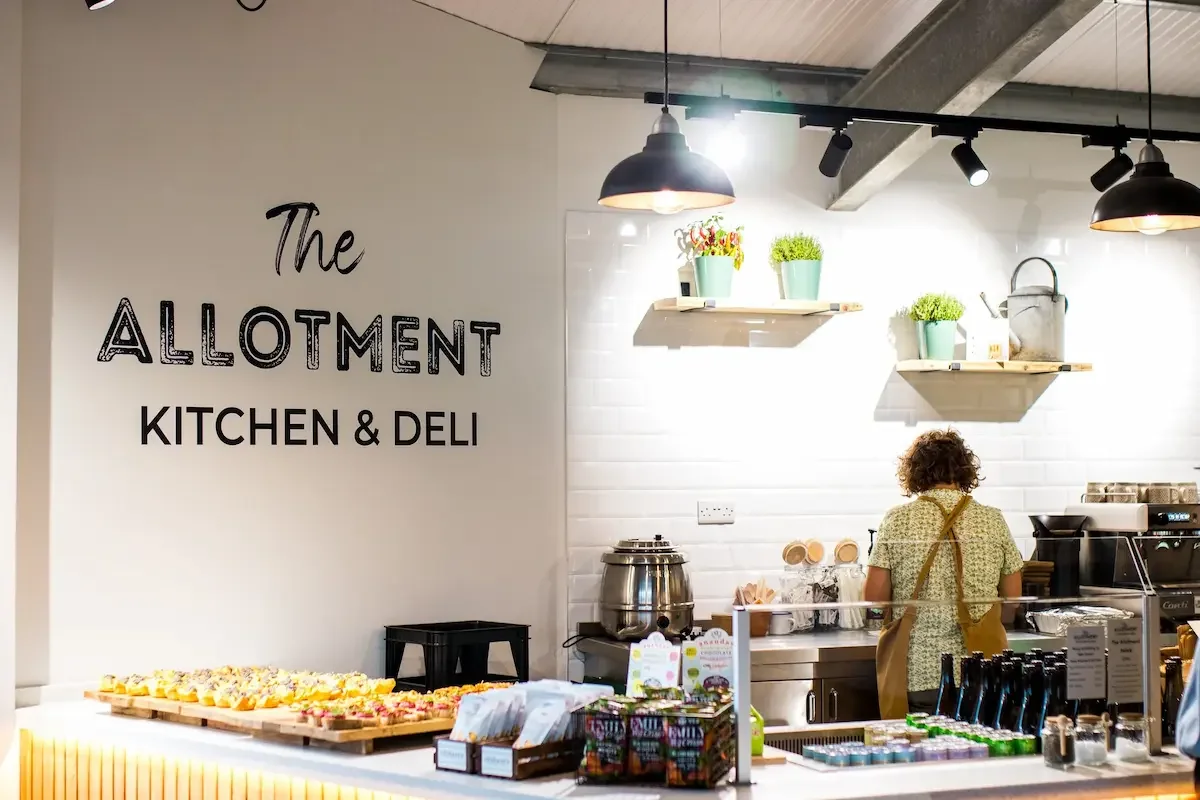 The front counter of The Allotment Kitchen and Deli in Collingham with a selection of cakes and drinks on display