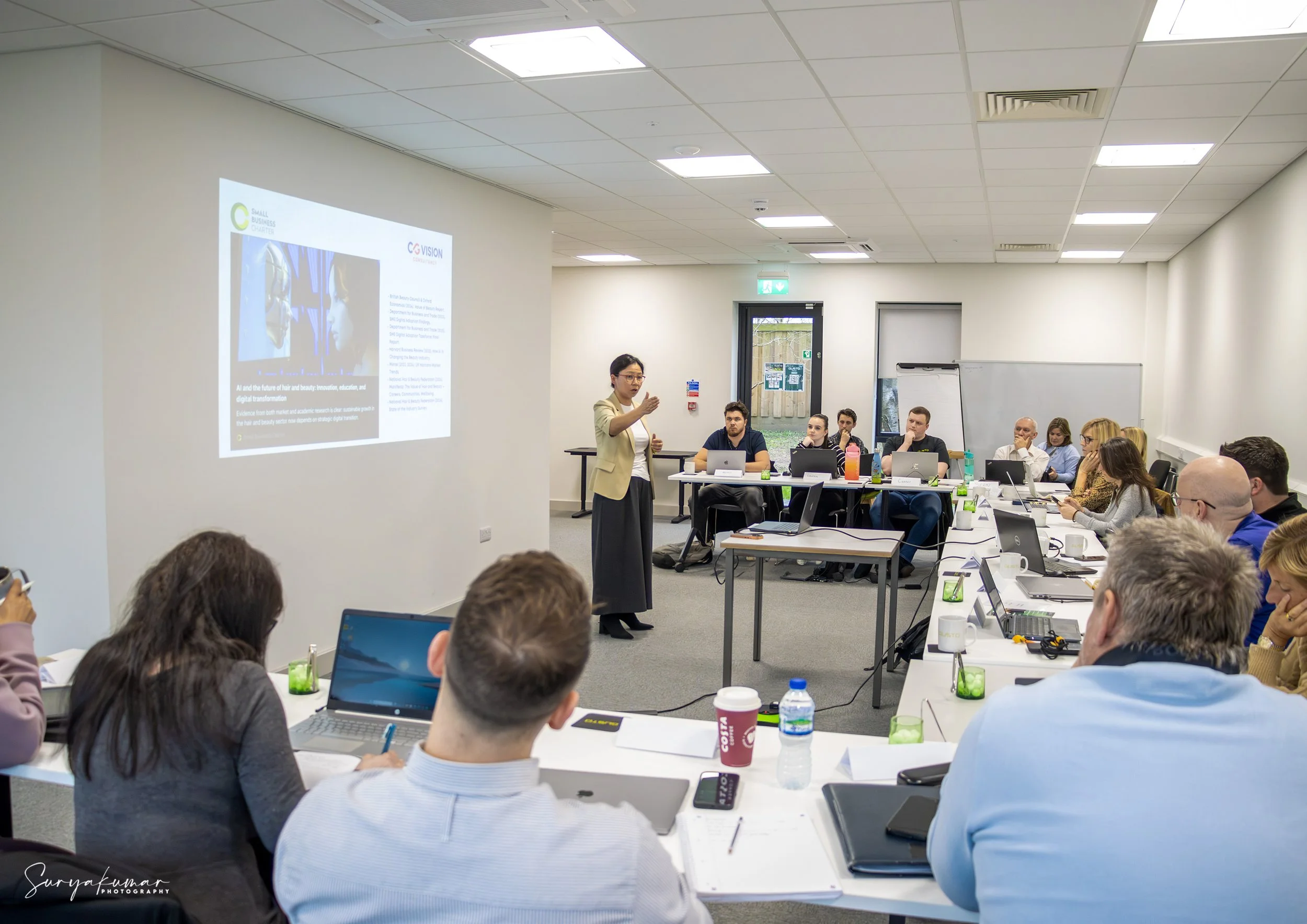 A professional workshop taking place at Gusto House in Collingham, featuring a presenter and attendees using the projector and flexible desk layout.