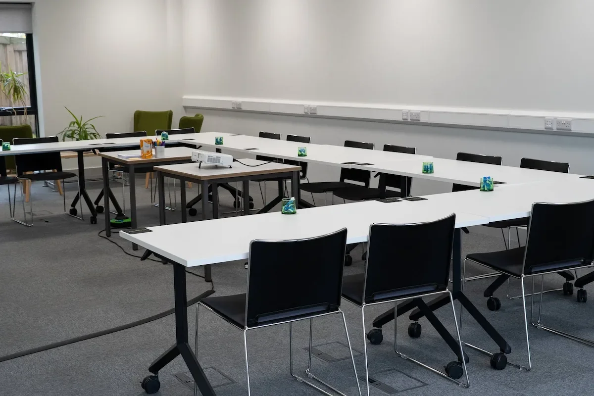 An empty training room, set out in the U shape surrounded with approx. 15 chairs.