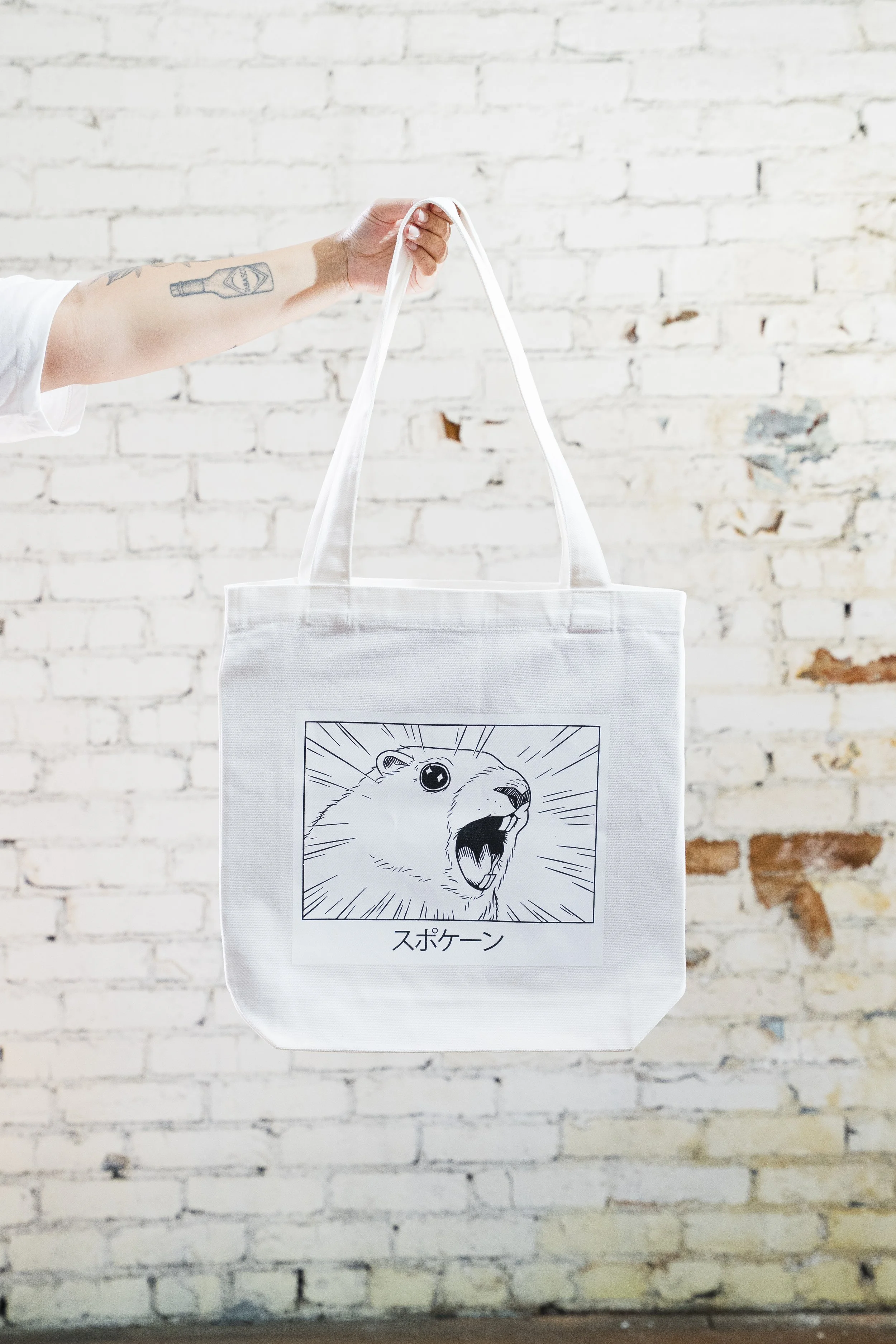a white tote bag with an anime marmot design, with japanese kanji for "spokane"