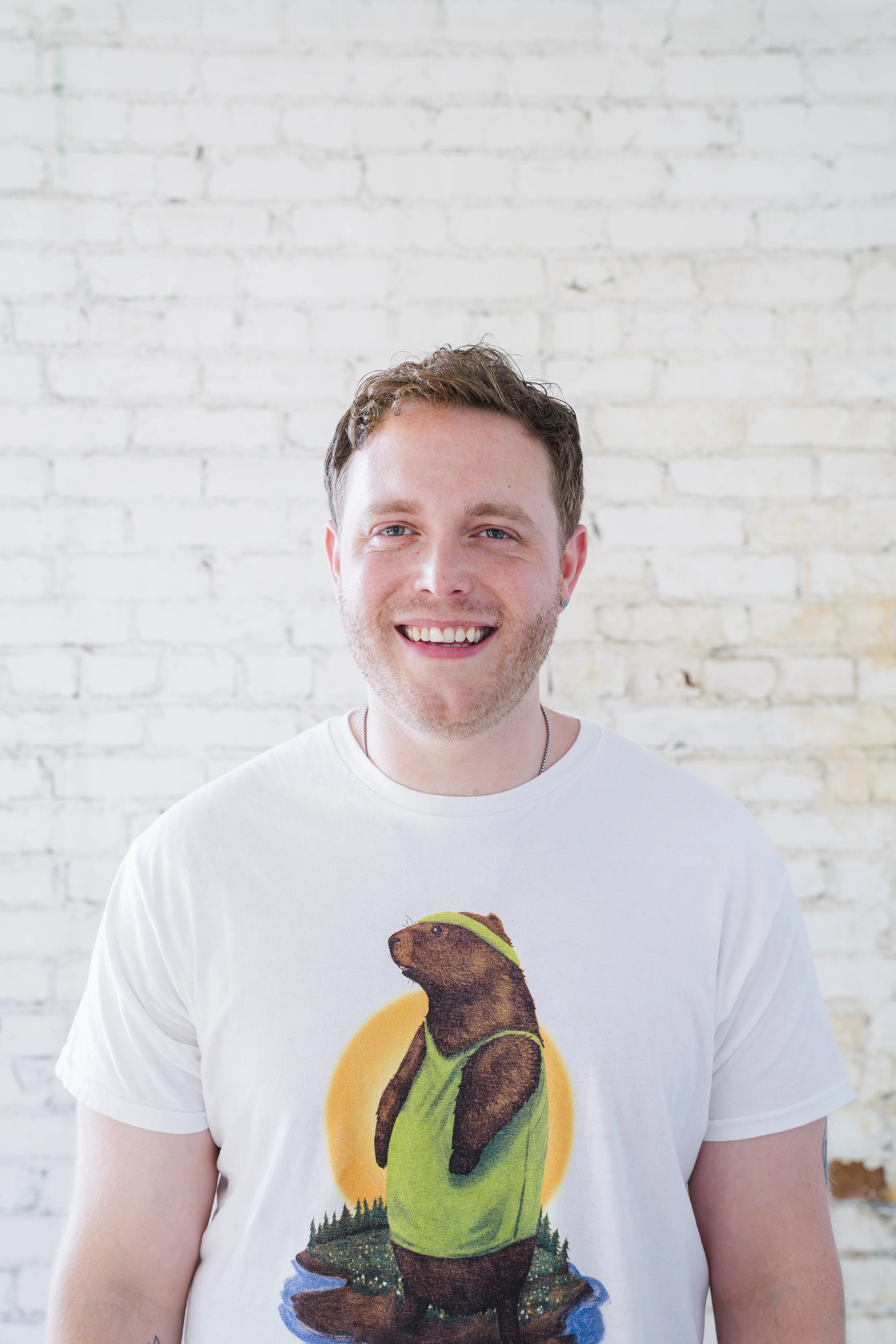 illustrator hugh russell smiling and wearing his white vintage marmot tee