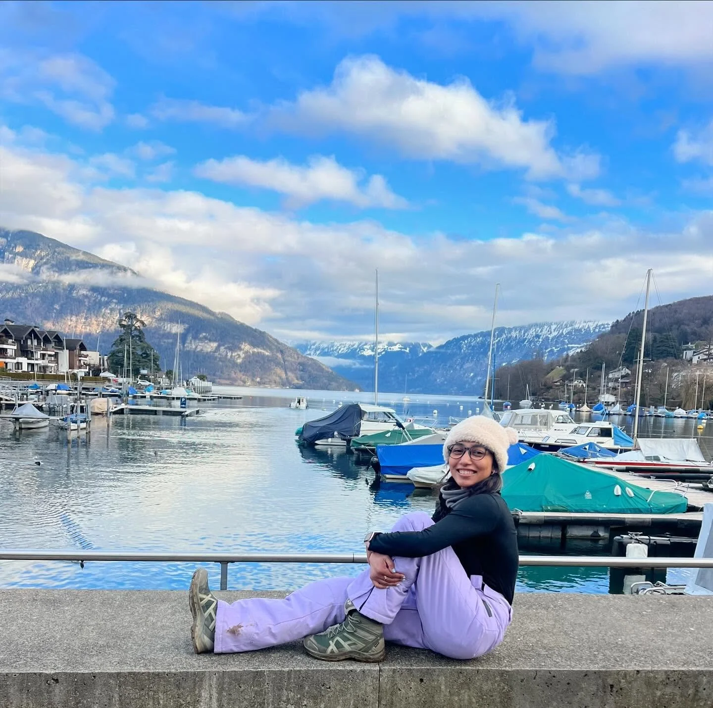 It&rsquo;s #magicalMarch . Time to unleash that little magic in your soul and turn them into a reality. Ready D? Always 🩵 
Taken at Spiez Switzerland. A quiet lake overlooking snowcapped mountains. #wanderwithdevi #d44Project #lovelife #livelife