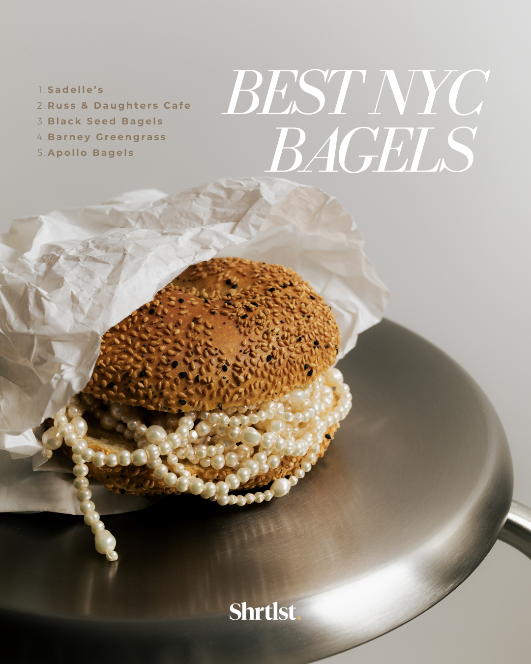 A sesame seed bagel topped with a pearl necklace, partially wrapped in white parchment paper, placed on a silver metal surface. Text overlay reads "Best NYC Bagels" with a list of five bagel shops.