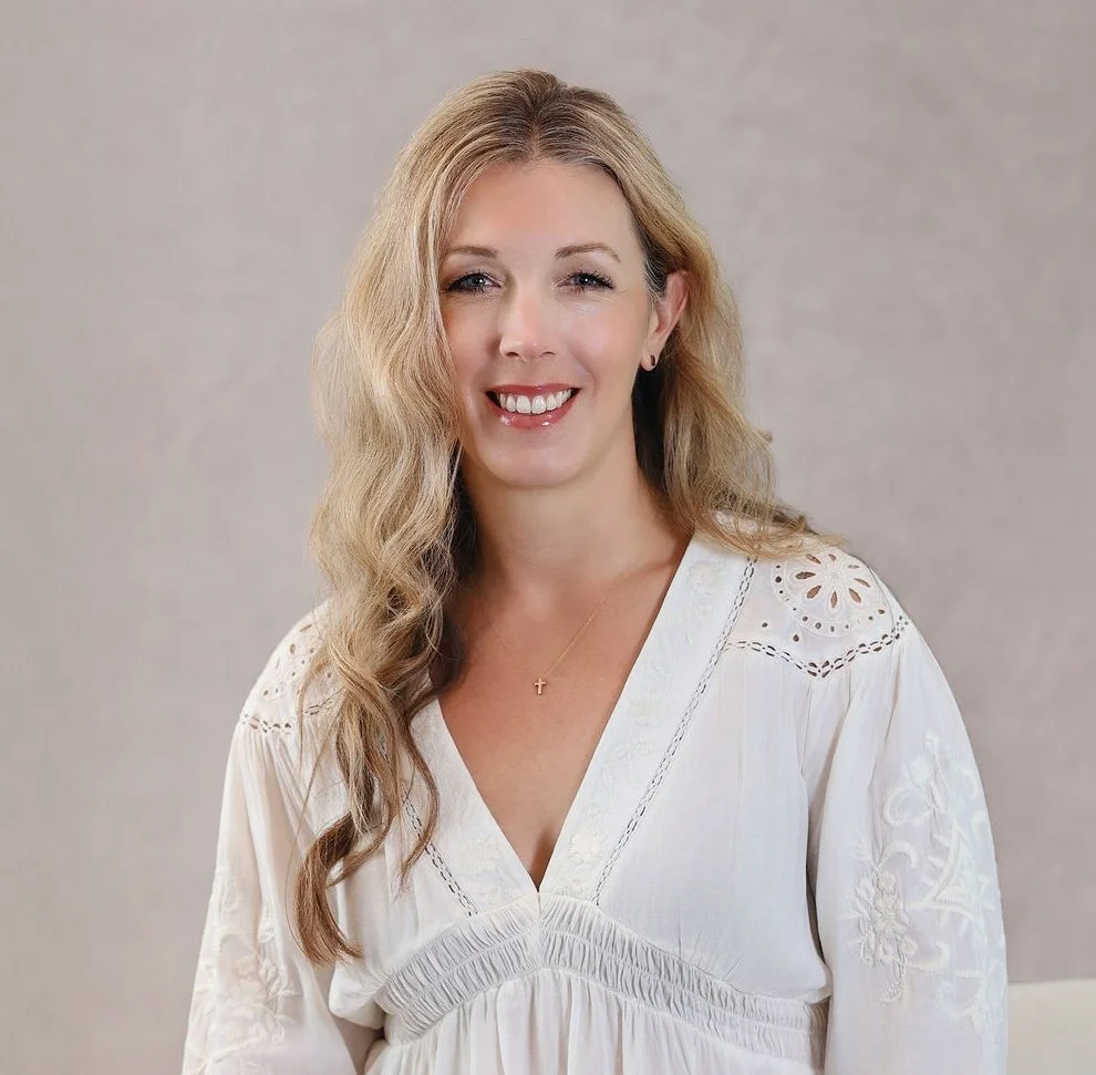 Jacqueline Fisch, Intuitive Writing author and mentor, smiling woman with long, wavy blonde hair wearing a white embroidered blouse, standing in front of a neutral background.