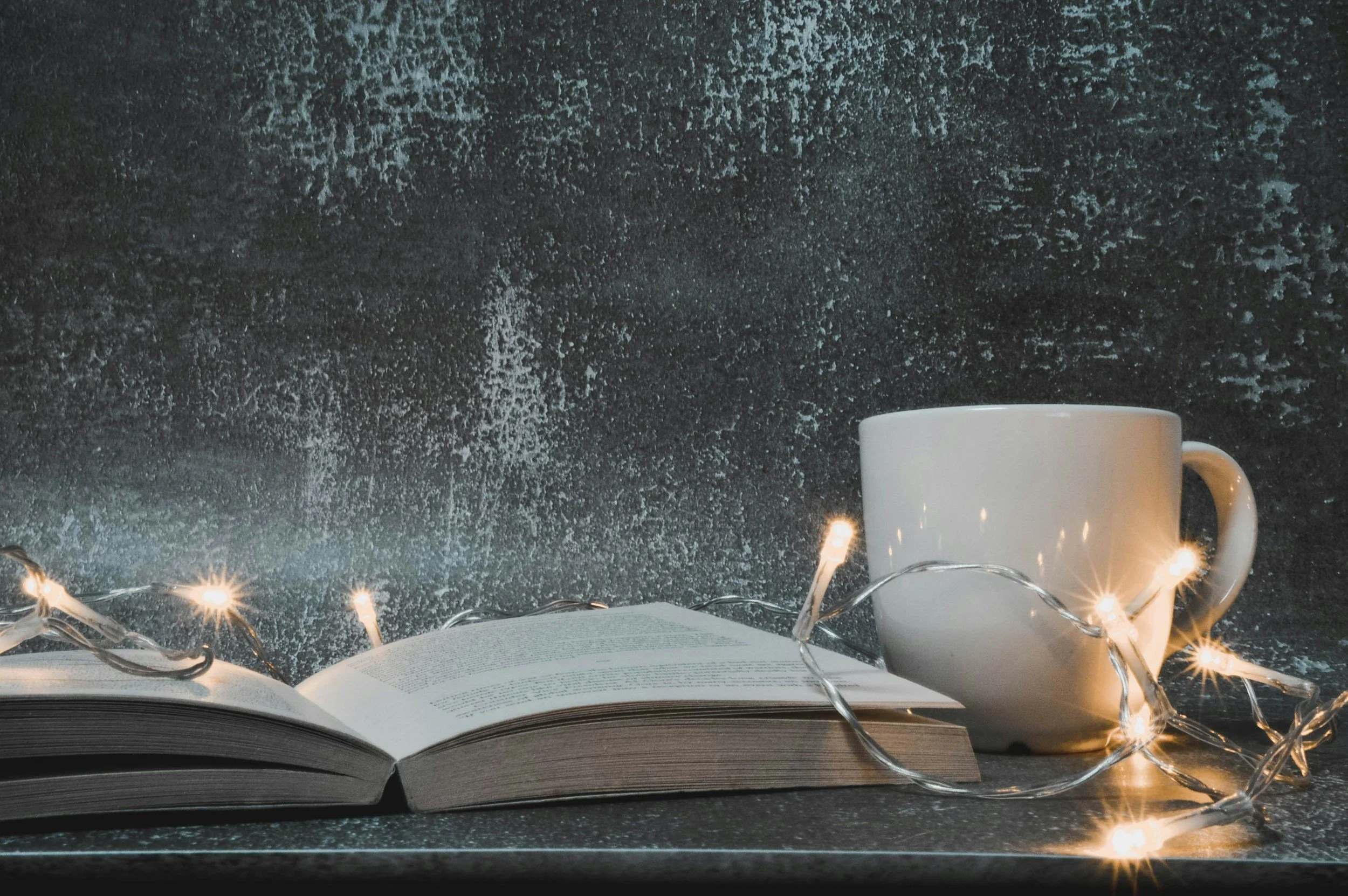 open book with string lights and a white mug