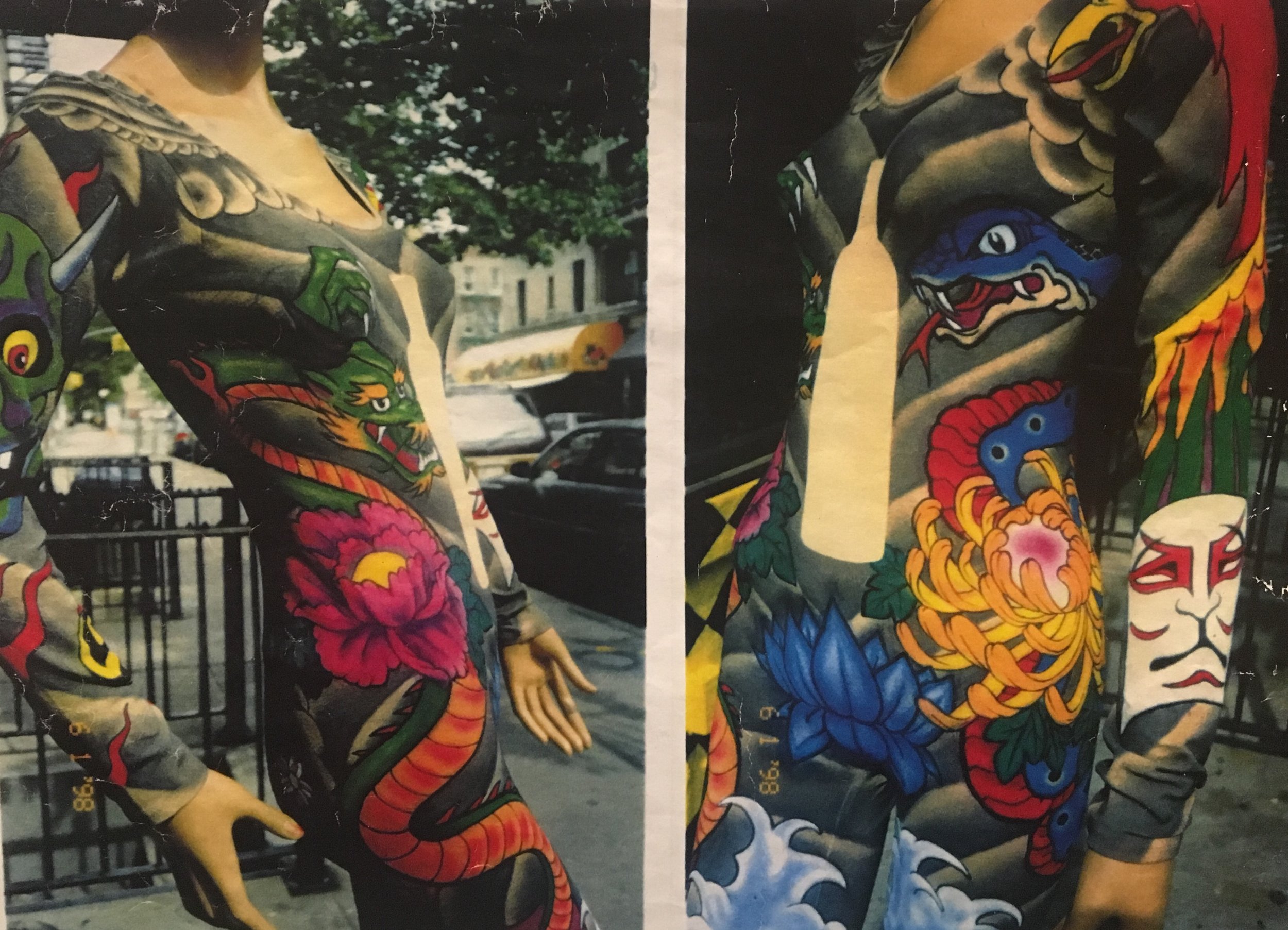 Two mannequins wearing colorful, tattoo-style bodysuits done for Absolute Vodka with designs of dragons, flowers, and traditional masks, displayed outdoors on a city sidewalk.