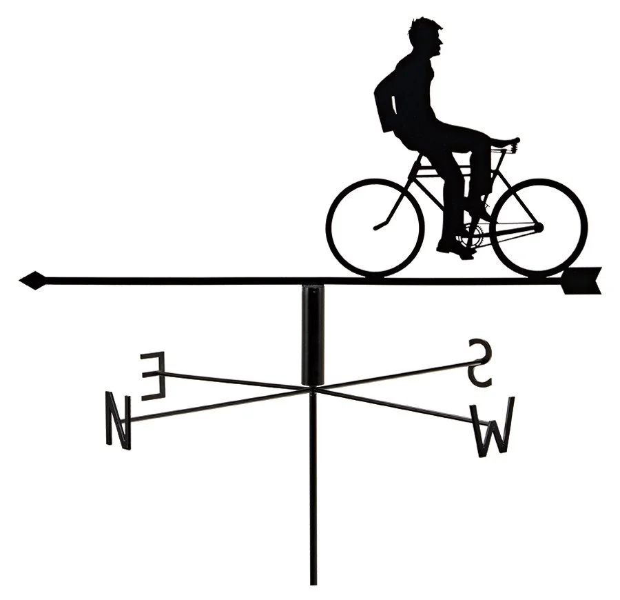 Silhouette of a person riding a bicycle on a weather vane. The weather vane has a directional arrow with North, South, East, and West indicators.