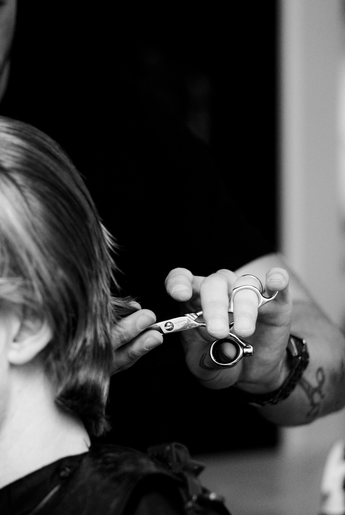 Close-up black and white photo of a stylist cutting hair at Travis Hairdressing.