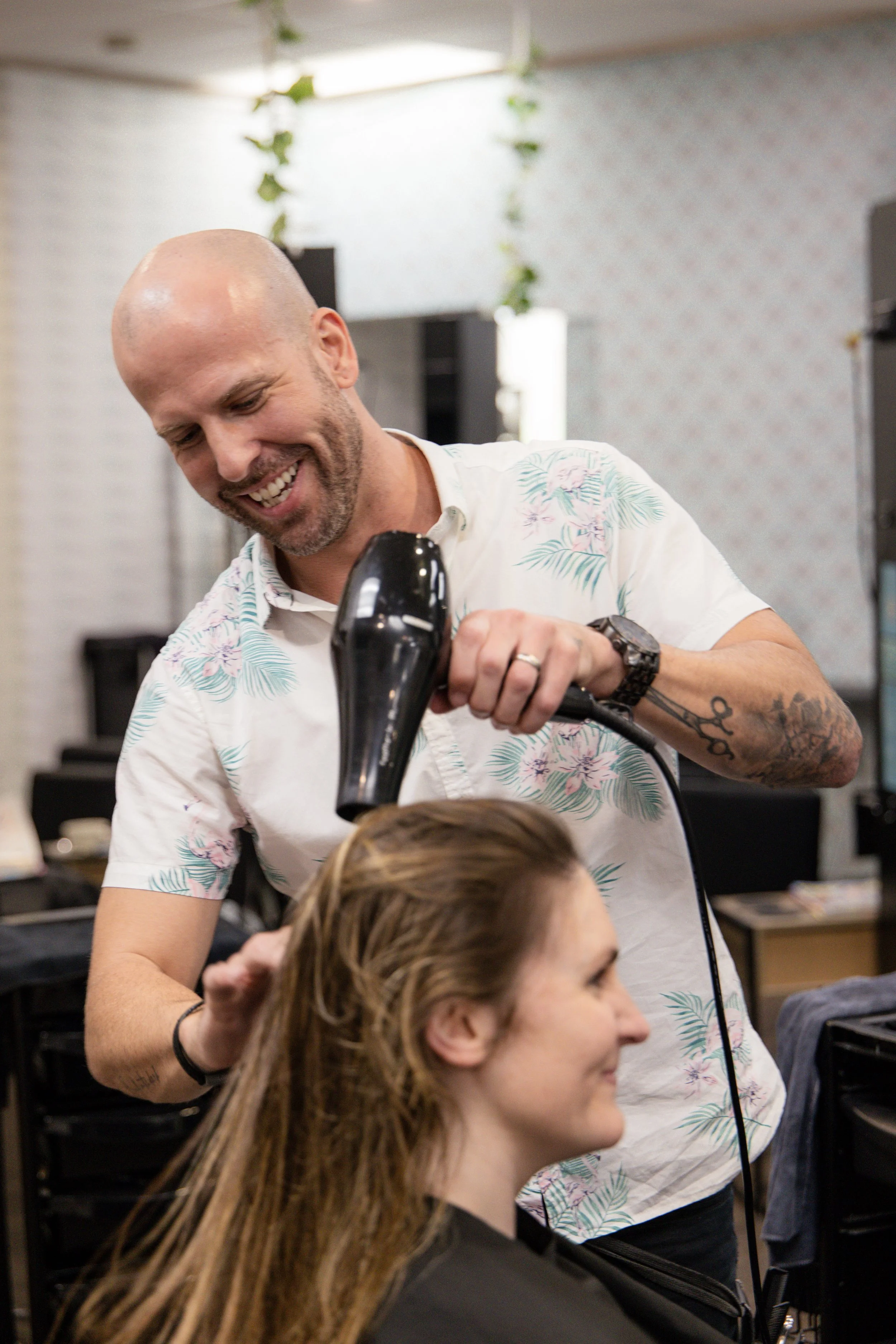 Smiling hairdresser blowdrying a client’s hair at Travis Hairdressing, a welcoming Blackwood hair salon