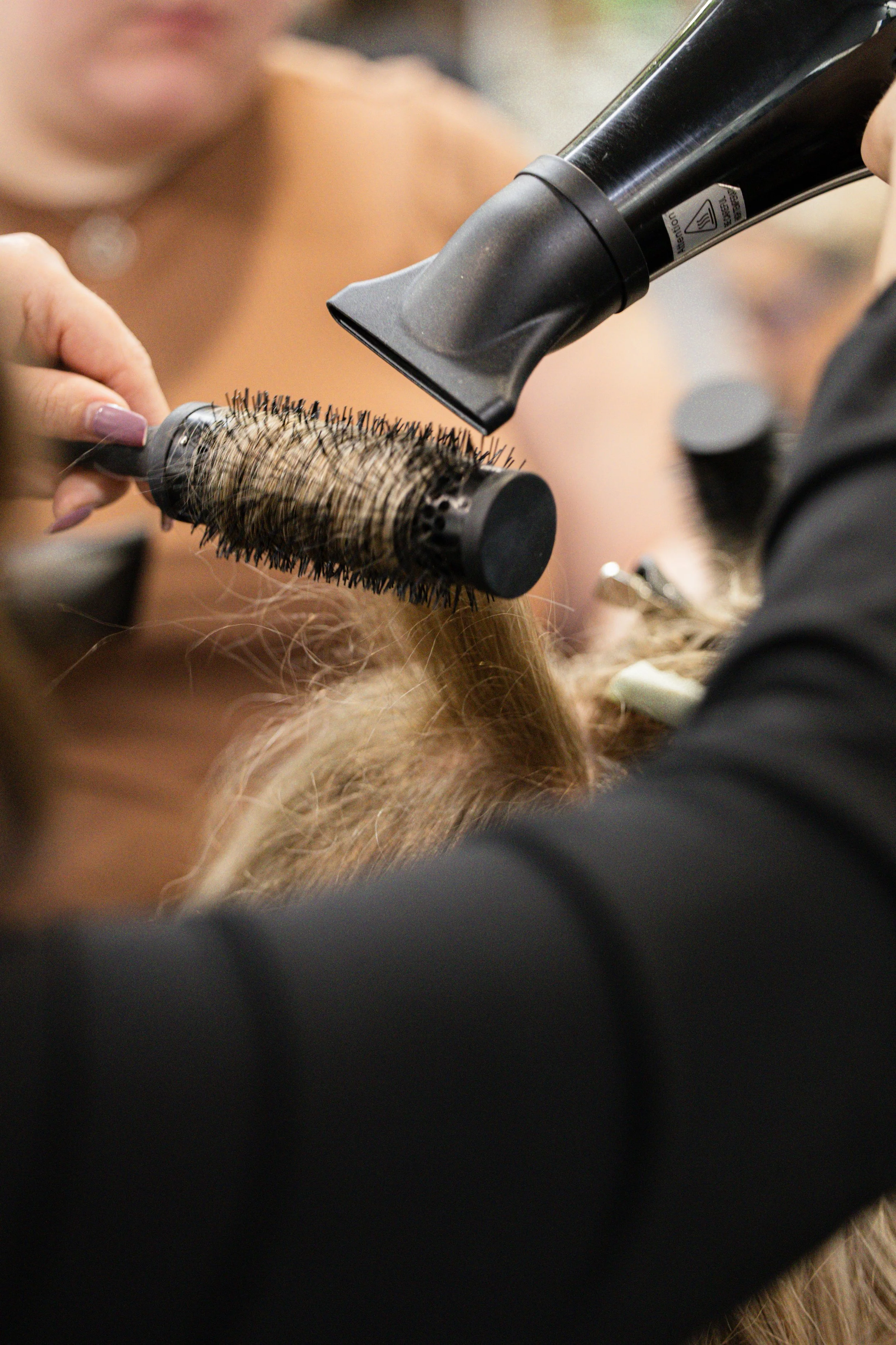Close-up of a blowdry with a round brush at Travis Hairdressing, creating smooth, styled ha