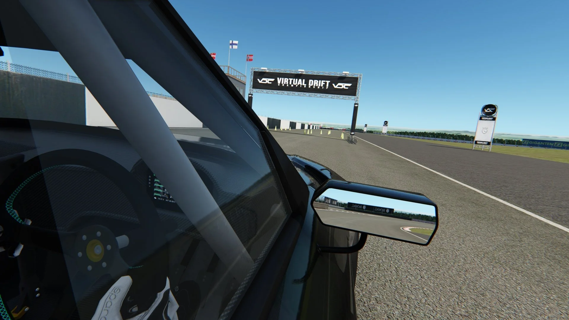 View from inside a race car on a track, showing the steering wheel and dashboard, with a finish line banner reading 'VIRTUAL DRIFT' ahead.