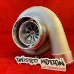 A twisted metal sculpture resembling a turbocharger with a small sign that reads 'Twisted Metal' in front of a red background.
