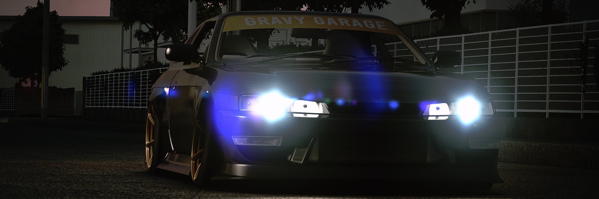 A black race car with bright headlights on a dark street, with a sign reading 'Gravy Garage' above the windshield.