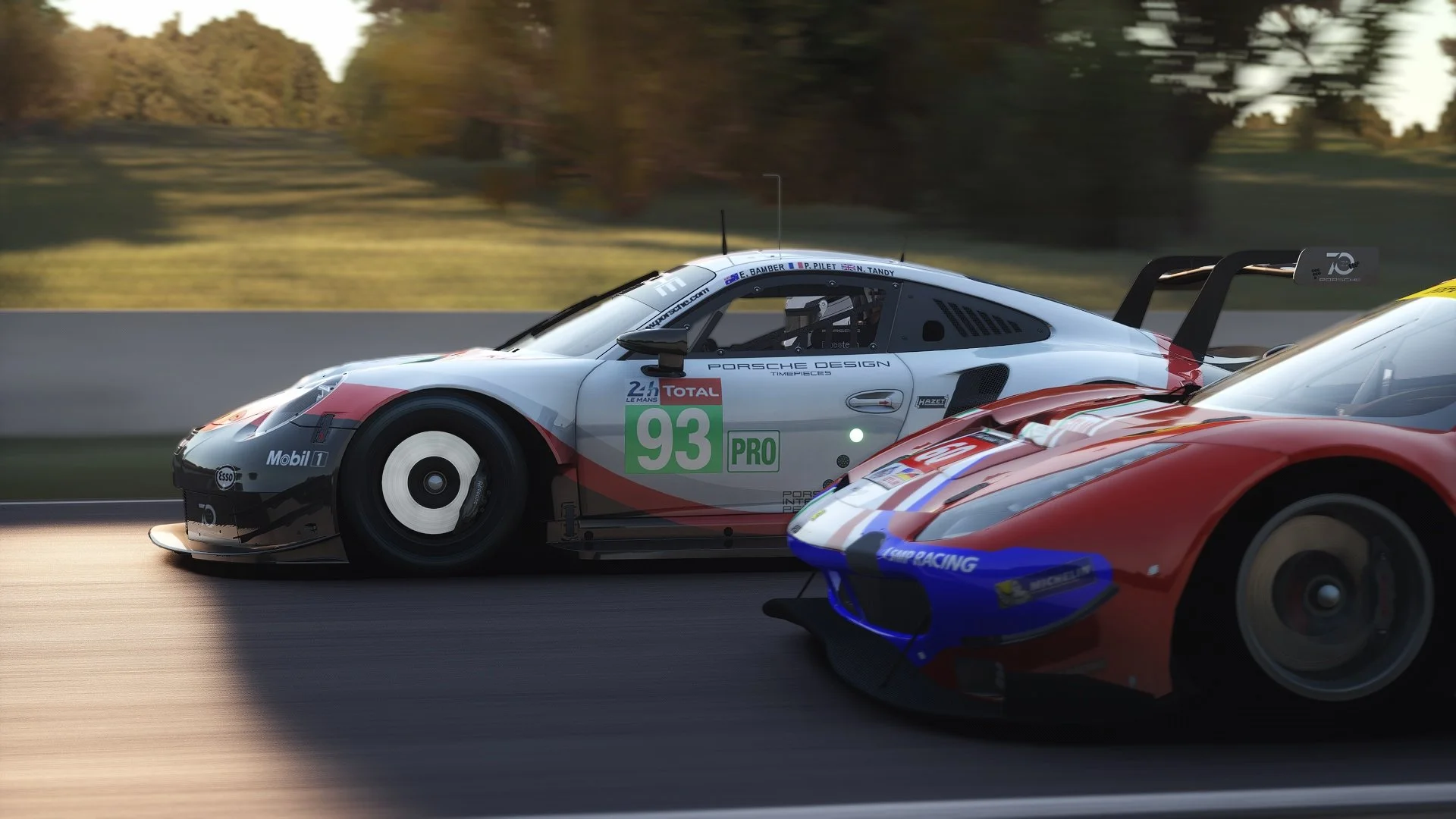 Two race cars driving on a track, one with a white and gray livery with green number 93 and the other with a red and blue livery, with a background of trees and a blurred track from motion.