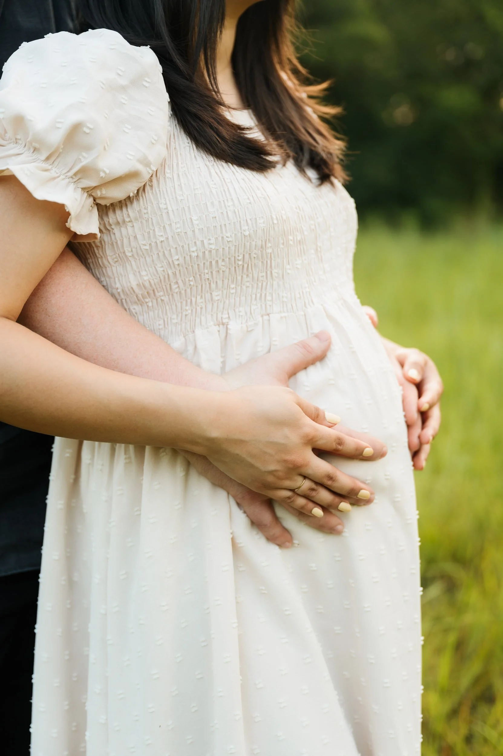Close-up maternity portrait showing baby bump during outdoor session