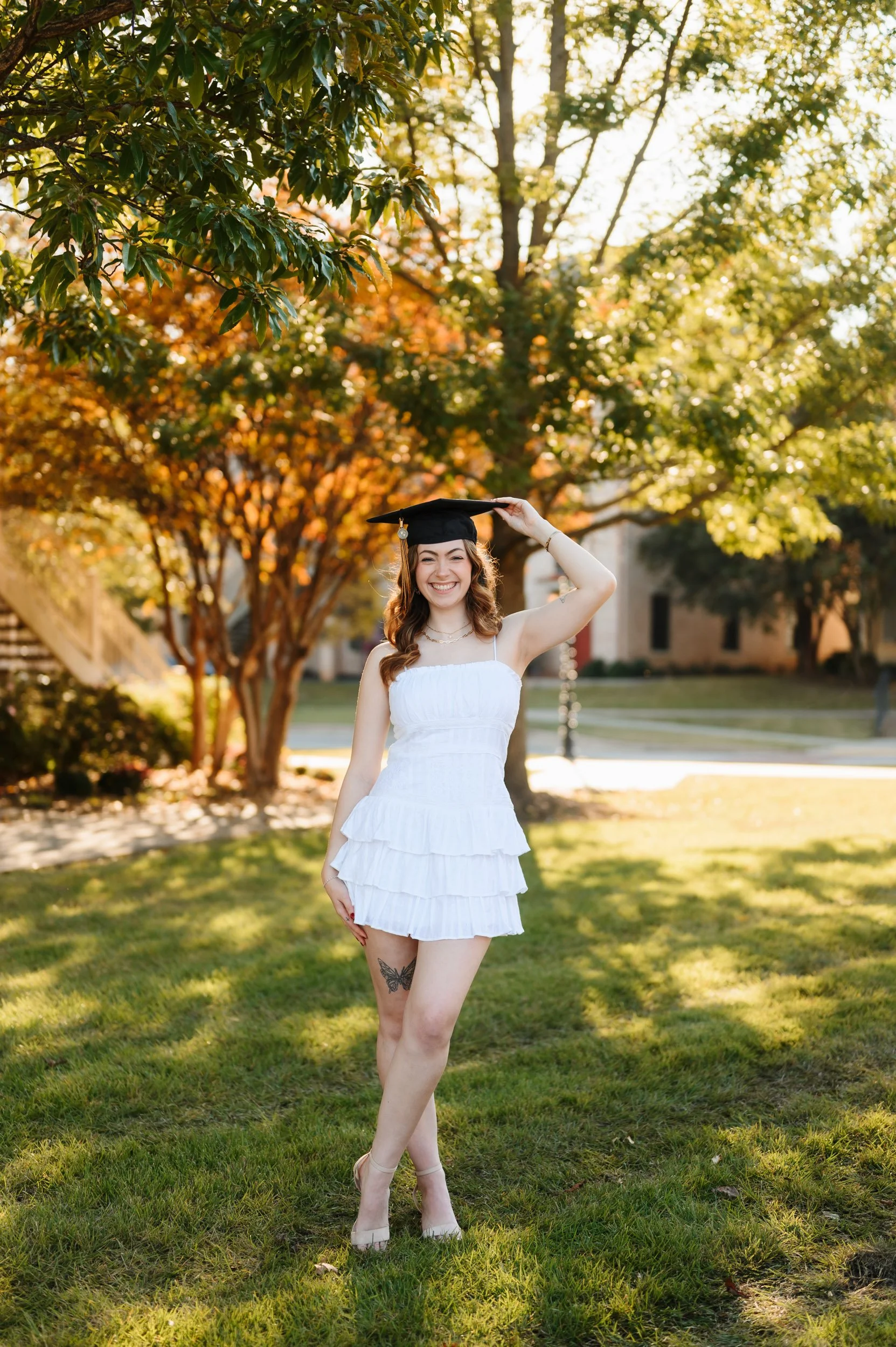 College graduate senior girl standing outdoors during golden hour portrait session