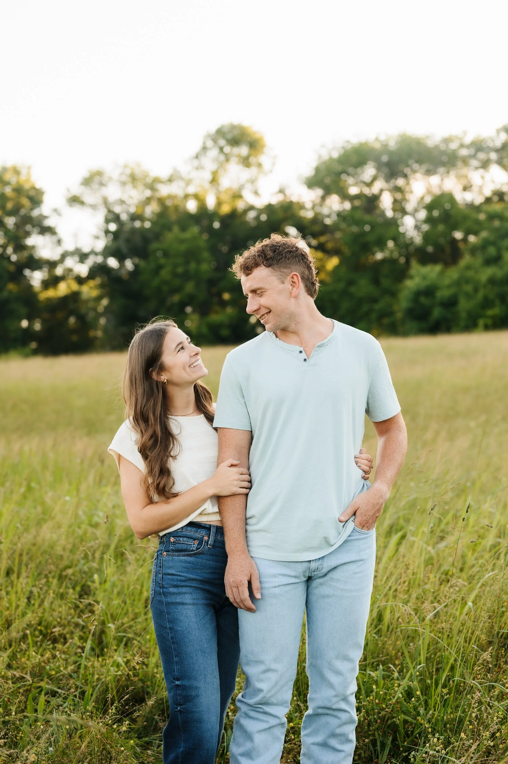 Couple embracing in open field during engagement session in Tennessee
