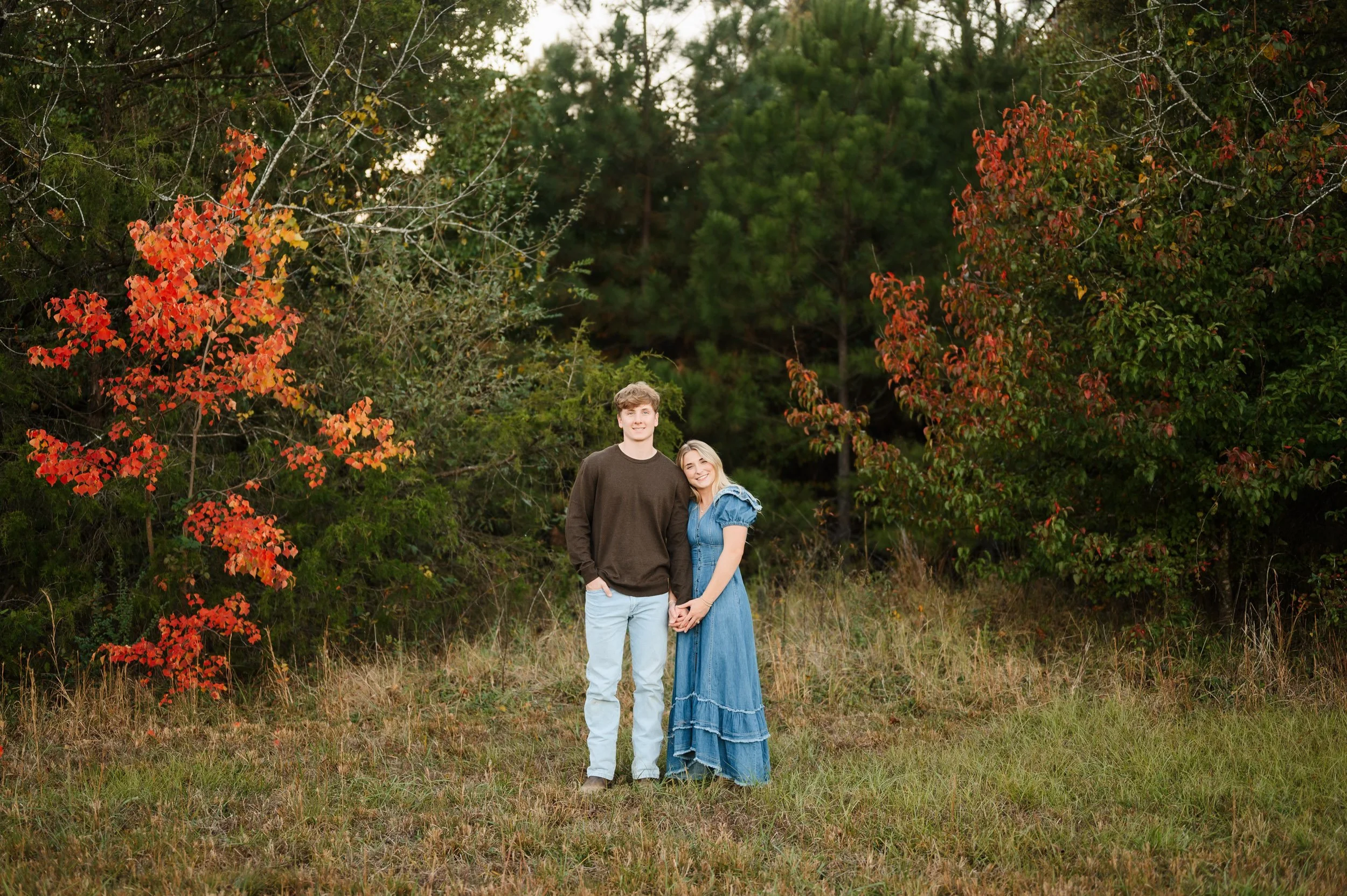 Couple standing together outdoors beside colorful autumn trees