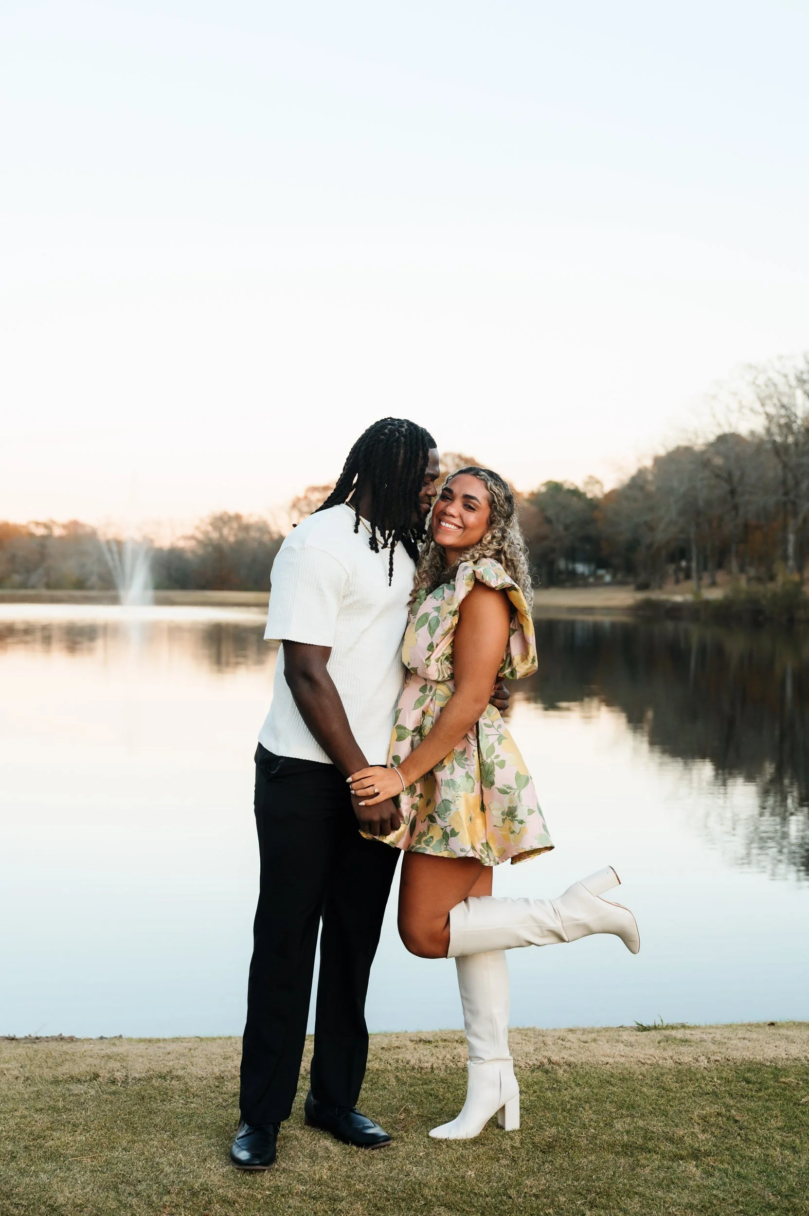 Black couple standing together beside lake during engagement session