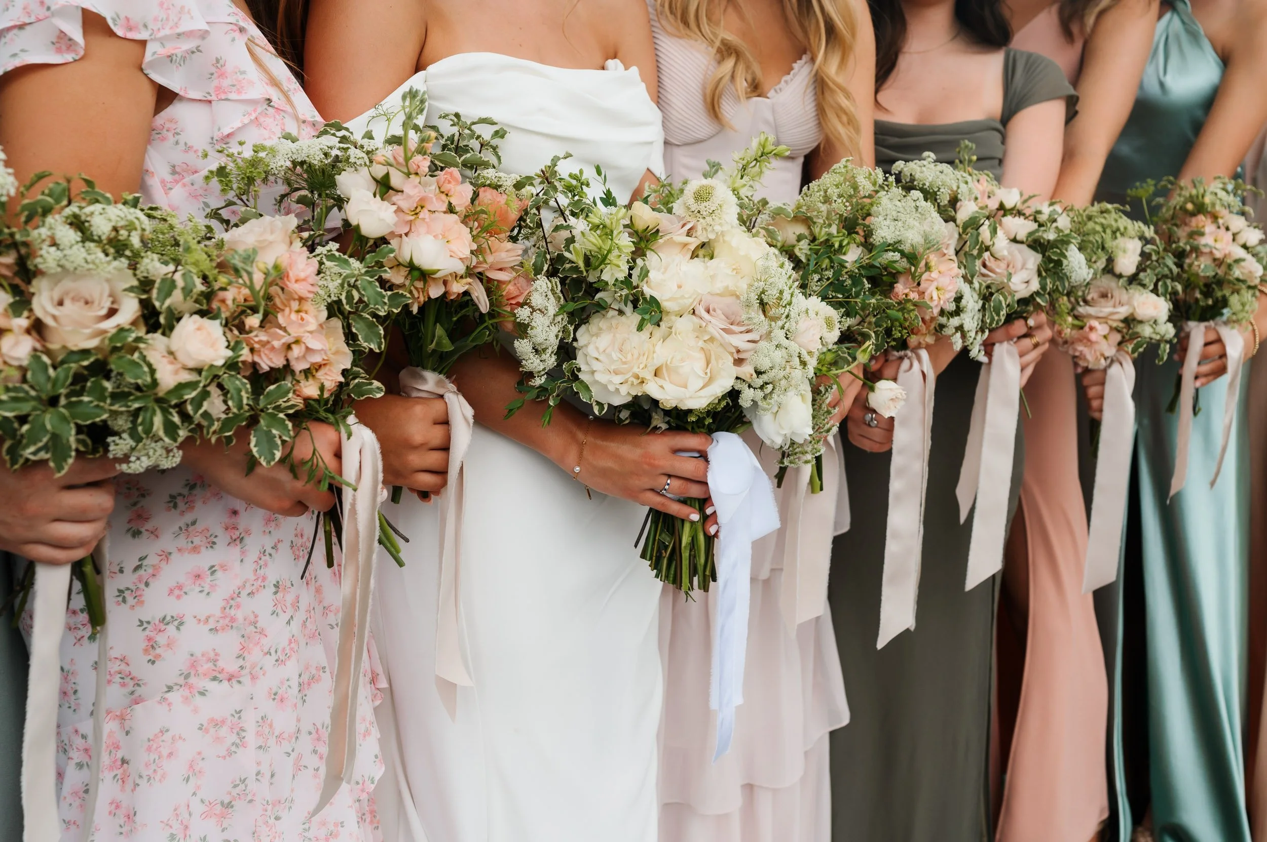 Bridesmaids holding bouquets during outdoor wedding photographs