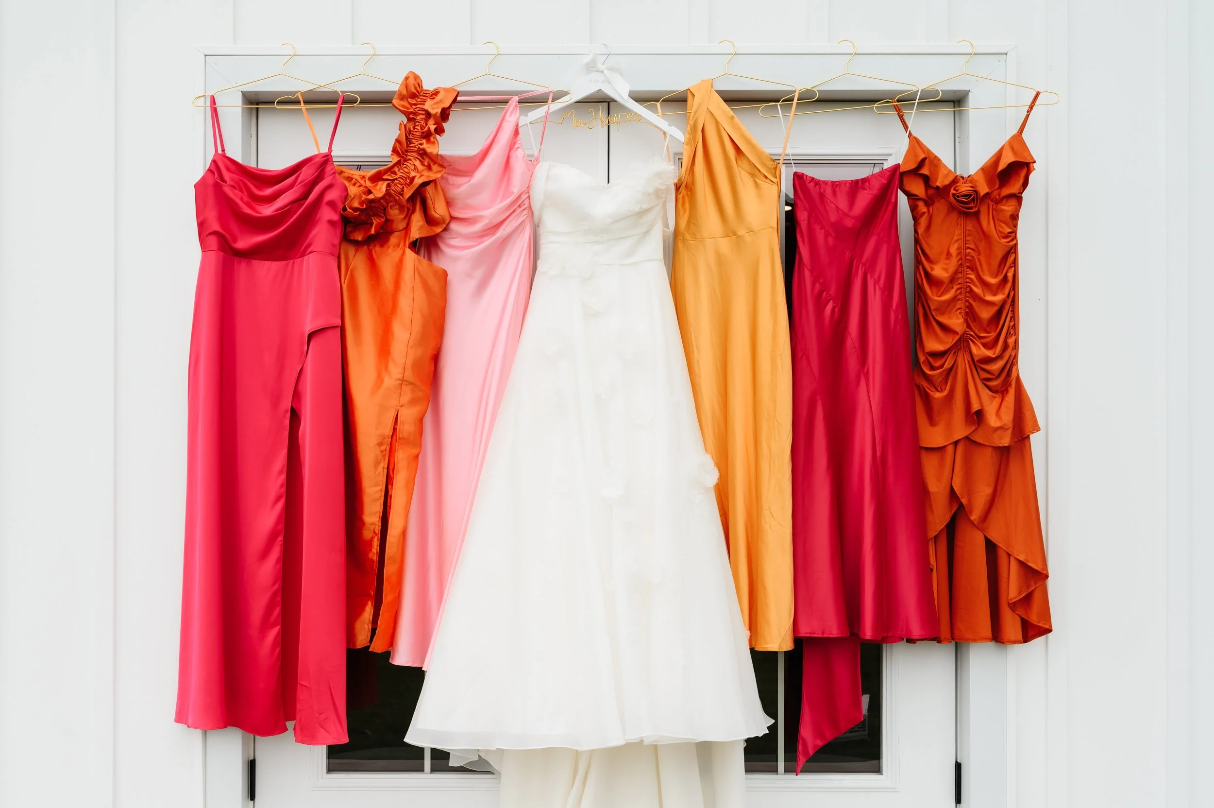 Bridesmaid dresses hanging up with Bride wedding dress