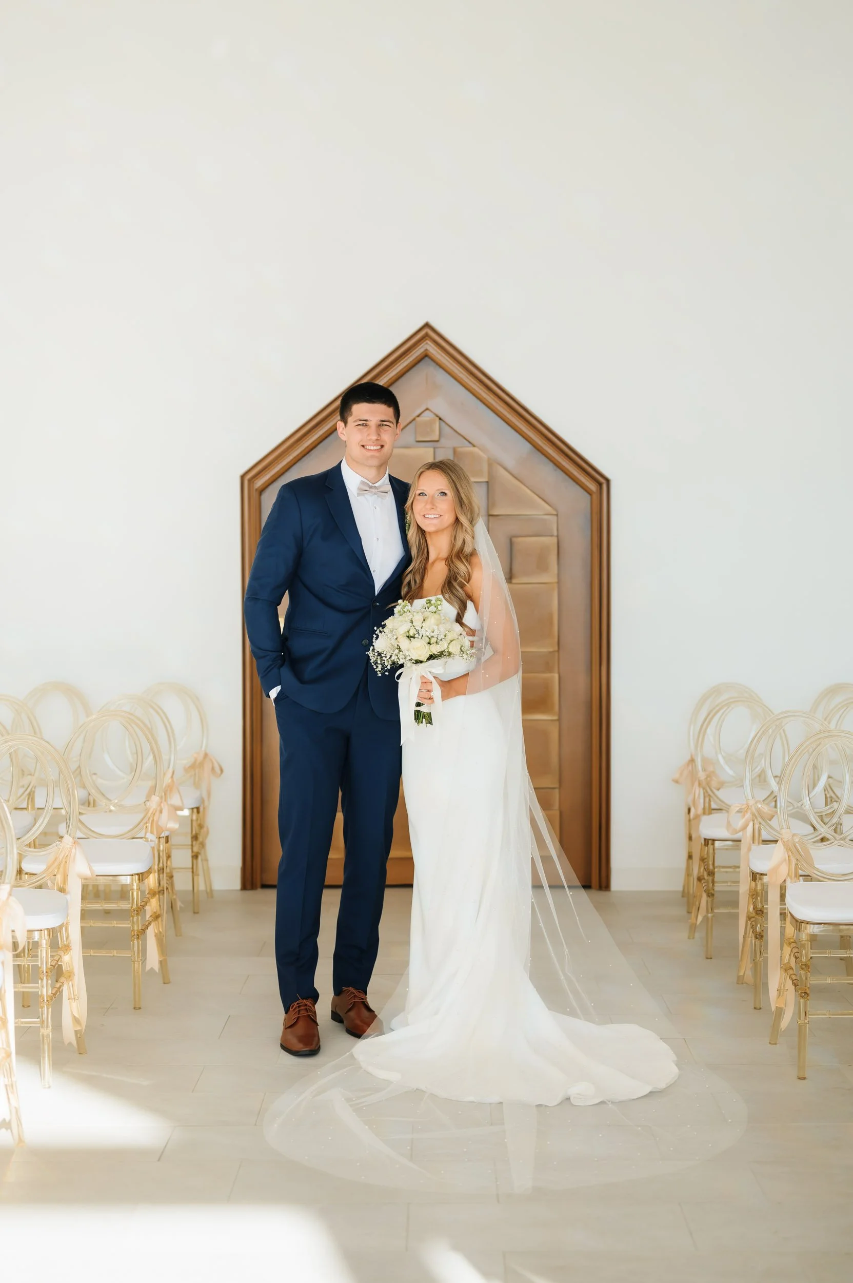 Bride and groom standing together inside elegant chapel during wedding portraits