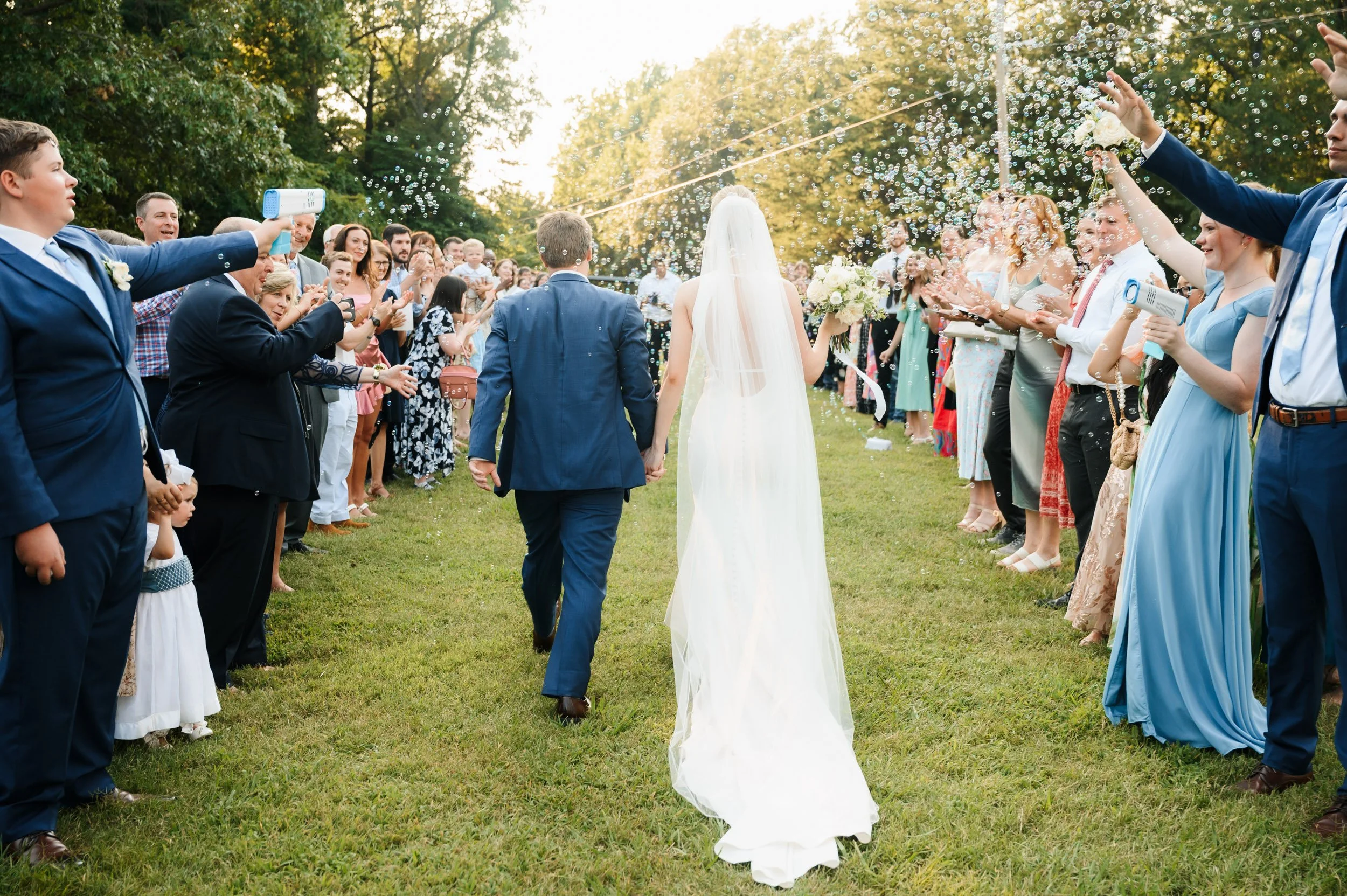 Bride and groom walking through guests bubble exit after outdoor wedding ceremony