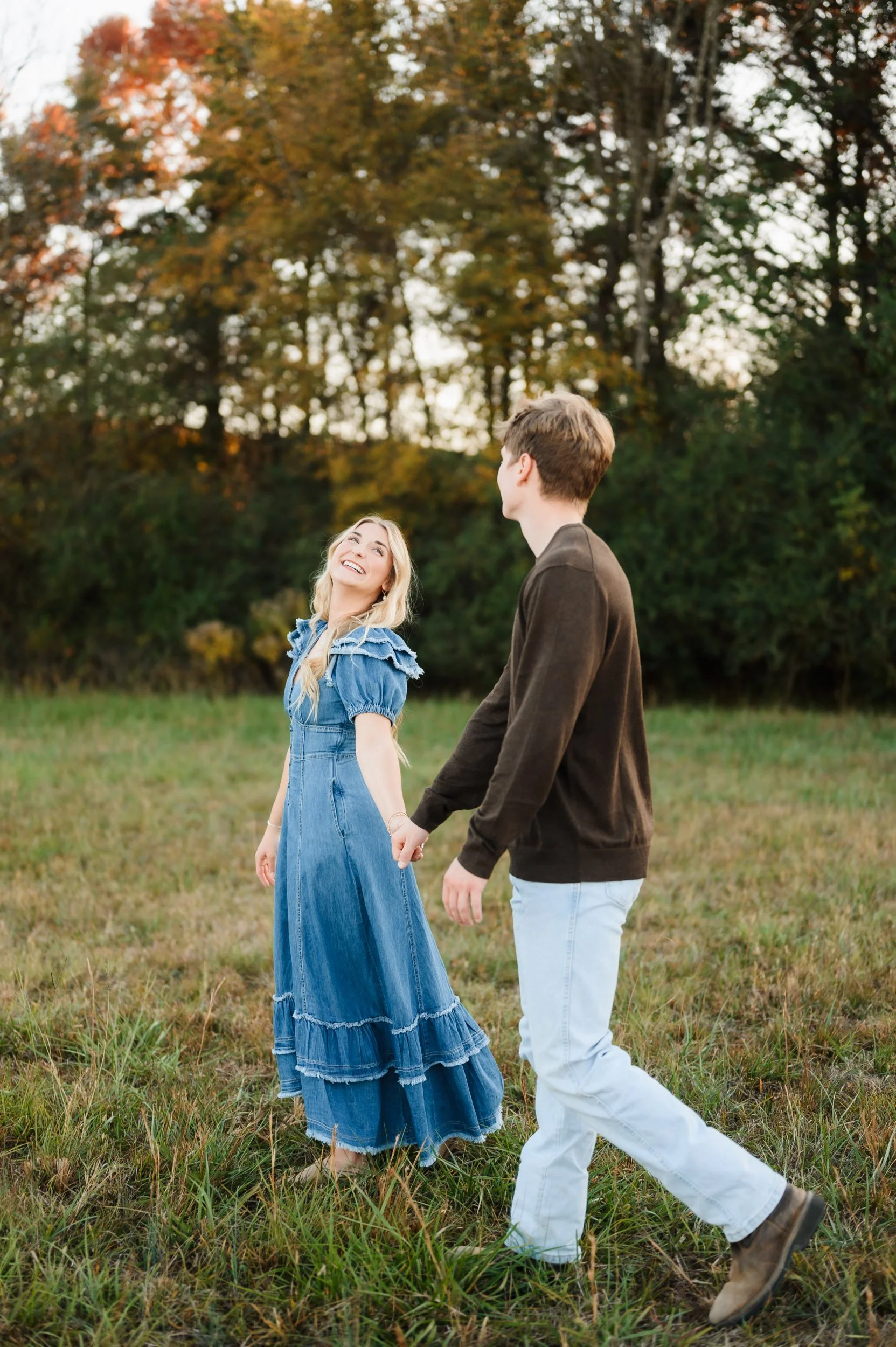 Couple holding hands walking together outdoors during fall engagement portrait session in Brentwood Tennessee