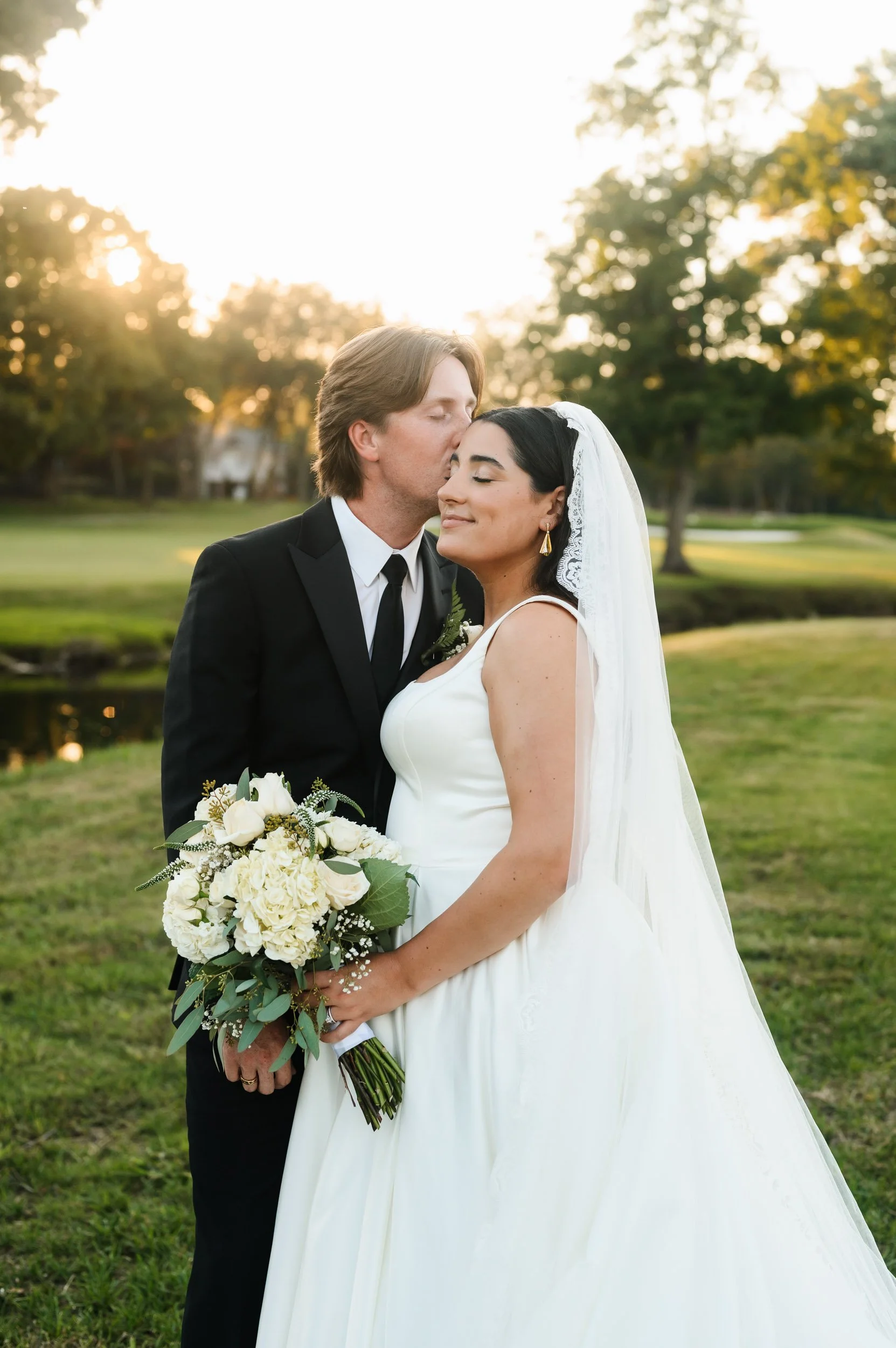 Bride and groom kissing during sunset wedding portraits outdoors in Brentwood Tennessee
