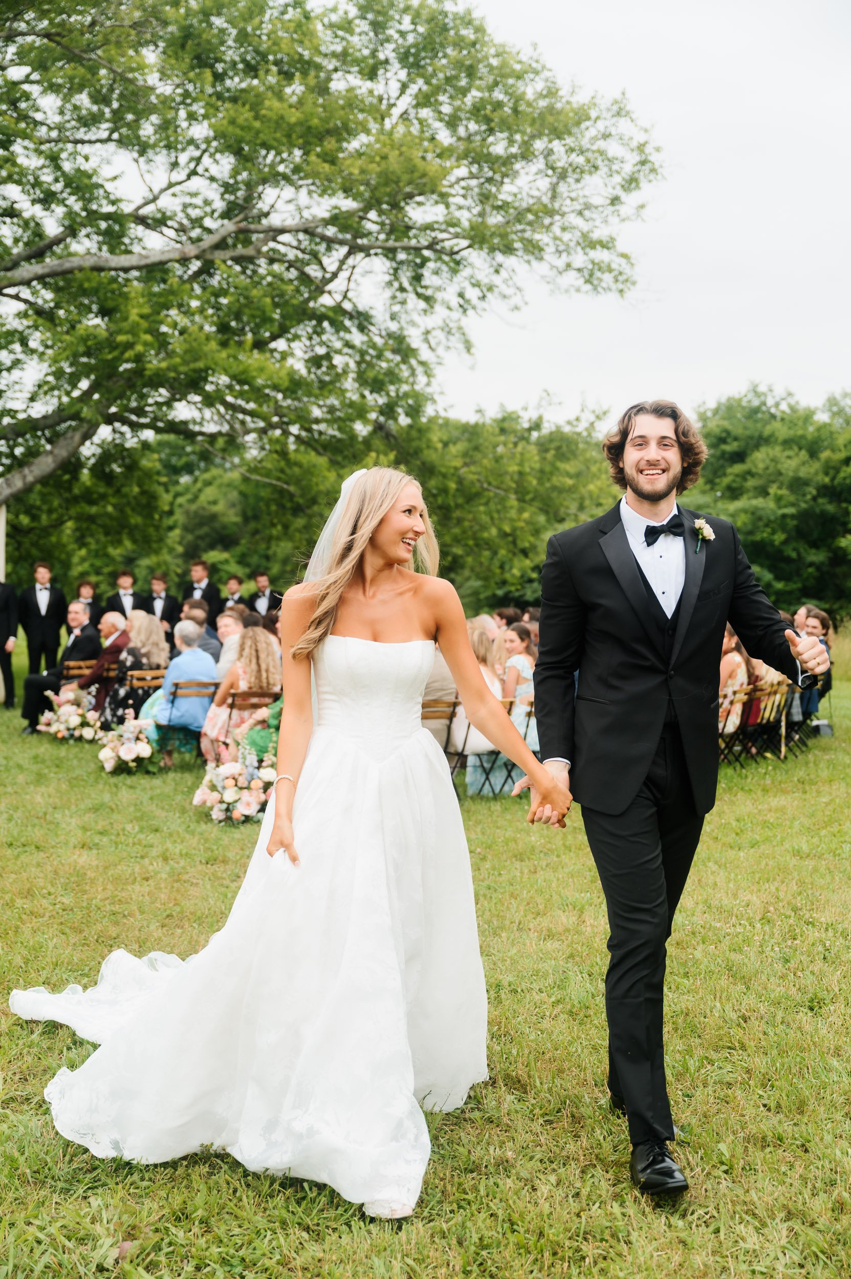 Bride and groom walking together exiting wedding ceremony outdoors during wedding day portraits