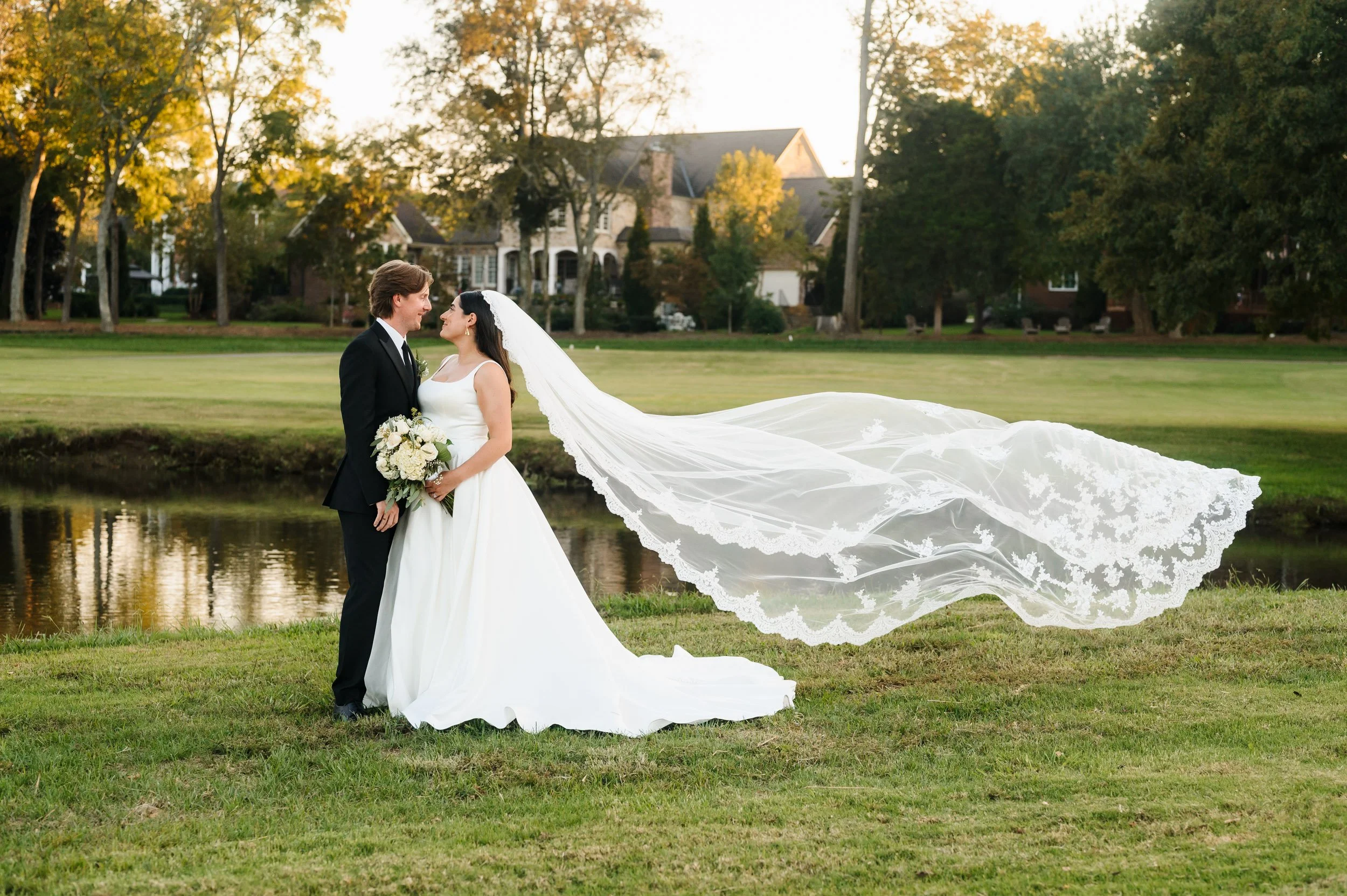 Bride and groom posing with long veil during sunset wedding portraits